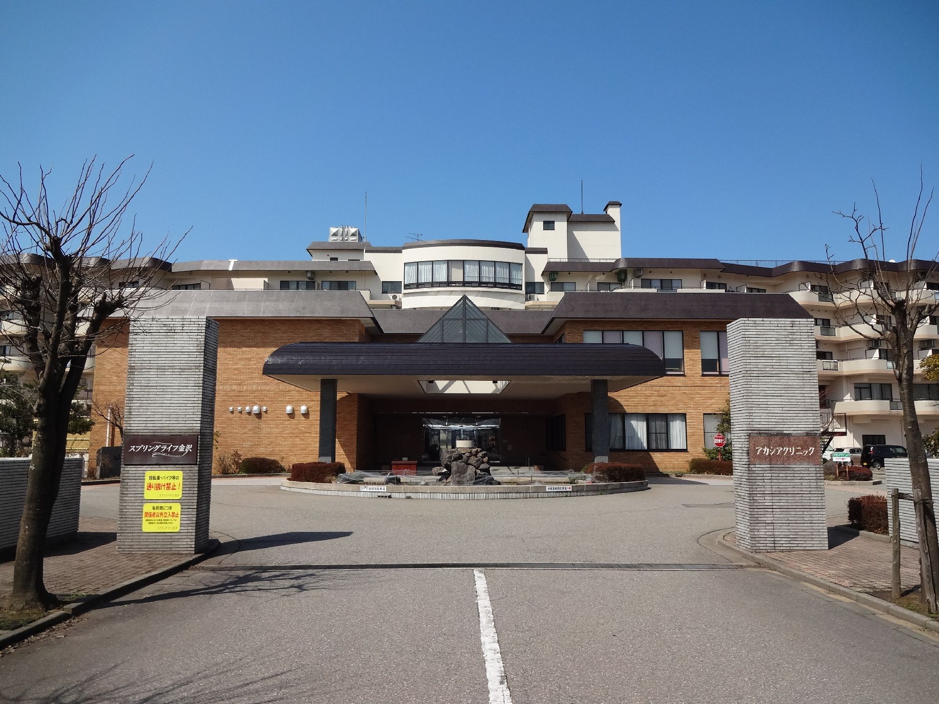 一部が６階建ての大きな建物で、門柱には施設名と並んで病院名が書かれている。正面の玄関上には半円形の大きなひさしがある。