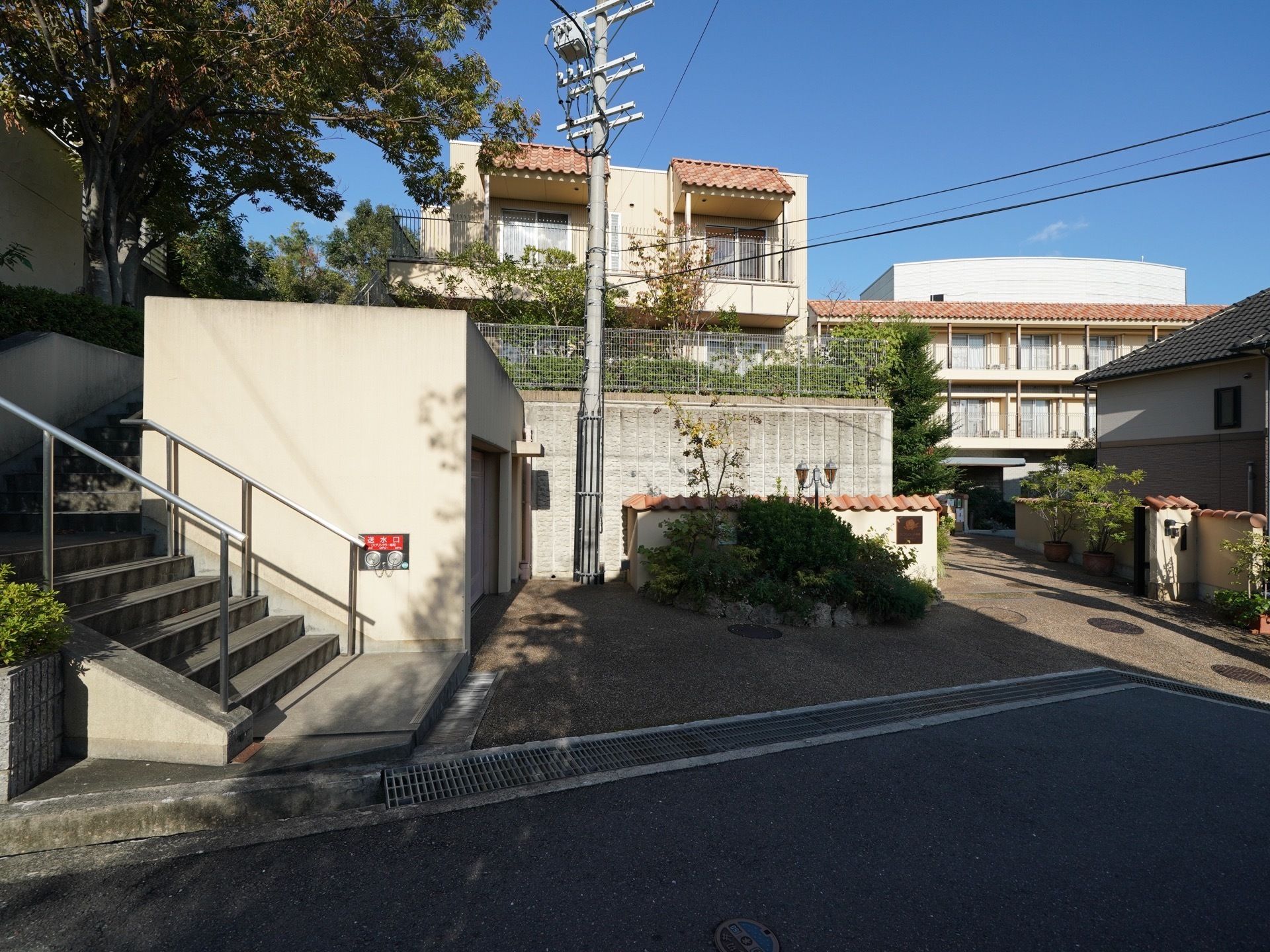 建物の出入り口にはブロック塀が建てられており、オレンジ色の瓦屋根がついている。建物にも同系色の屋根があり、統一感がある。