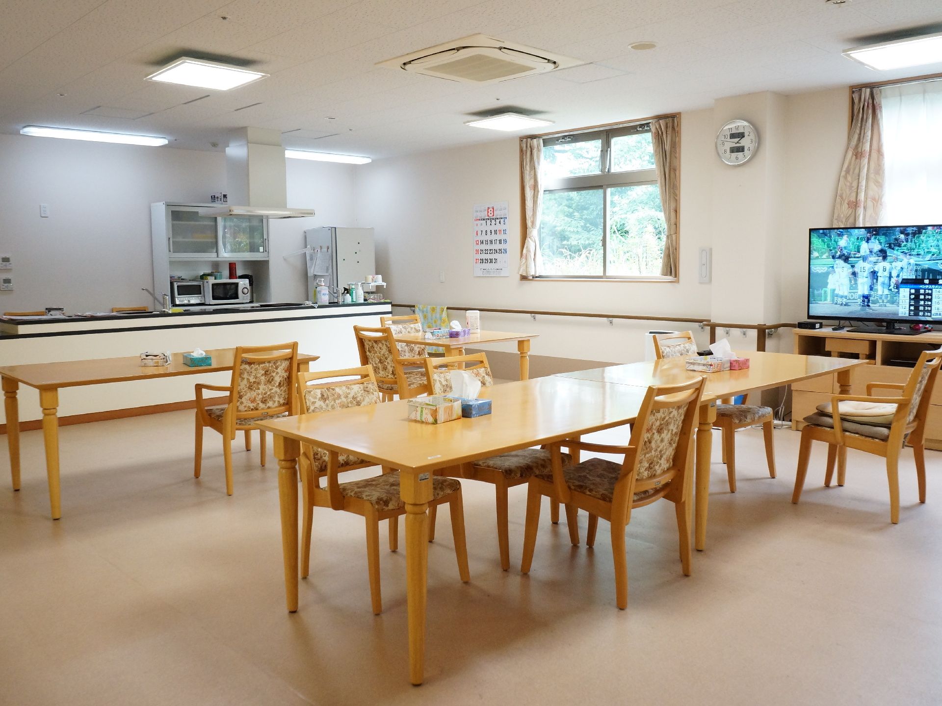 広々としたダイニングルームの天井には、空調設備と照明器具を設置している。また壁には窓があり、カーテンが用意されている。