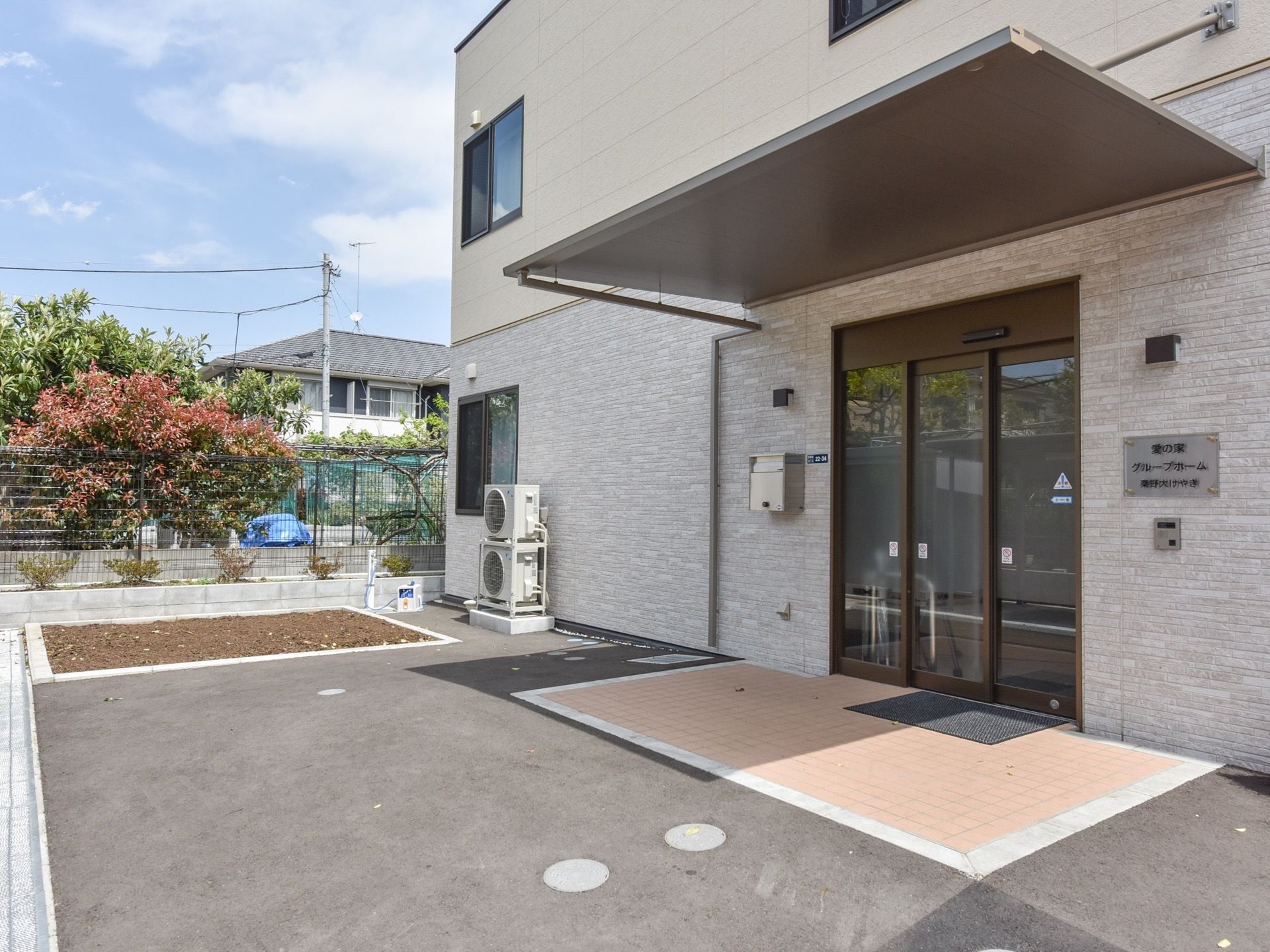 玄関は自動ドアが設置されており、屋根があるので雨の日も濡れずに施設内に出入りできる。玄関前のスペースには段差がなく安心である。