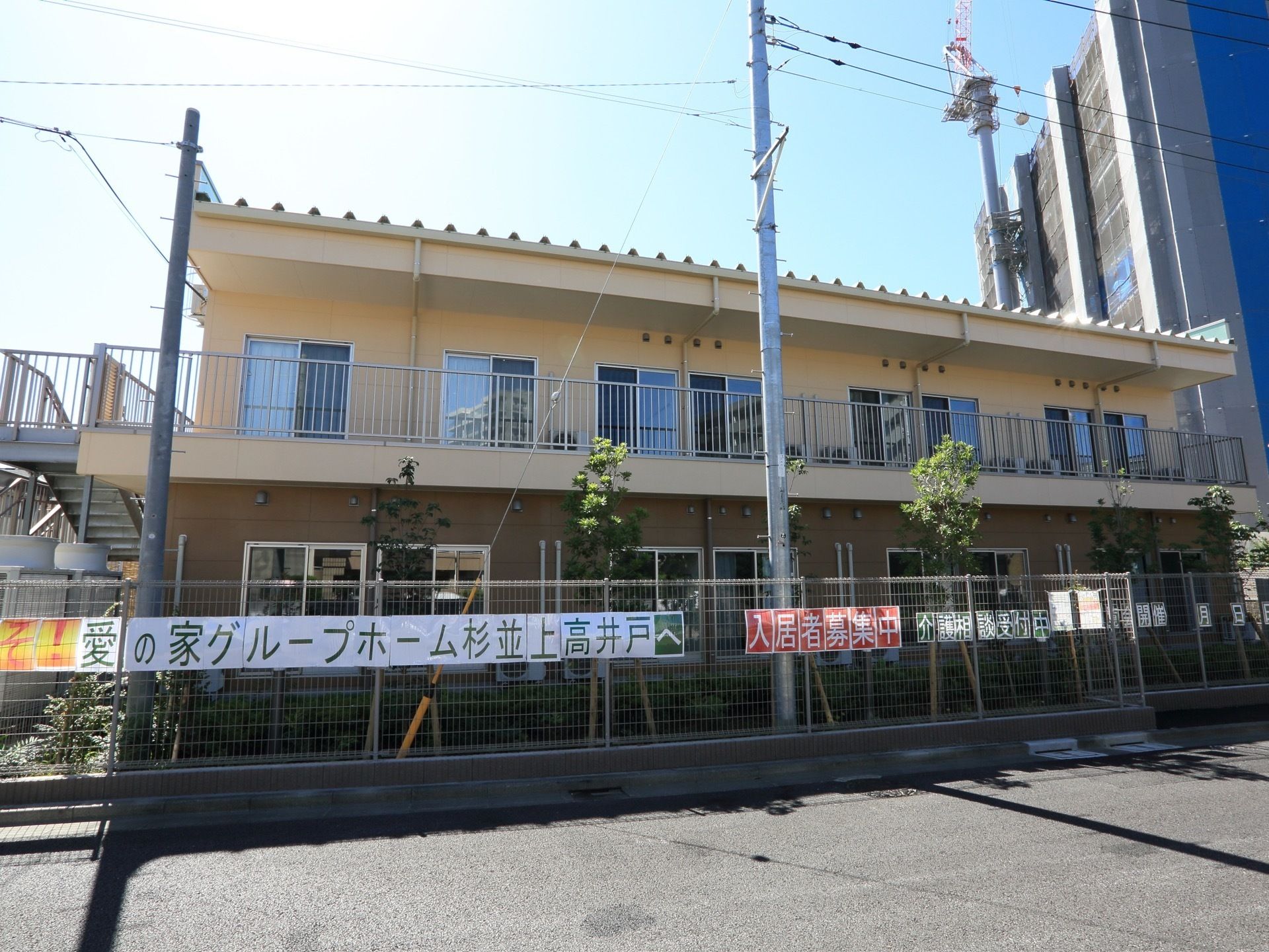 ベージュの外壁が柔らかな印象の軽量鉄骨２階建ての建物。２階のベランダから非常階段へ出られるようになっている。