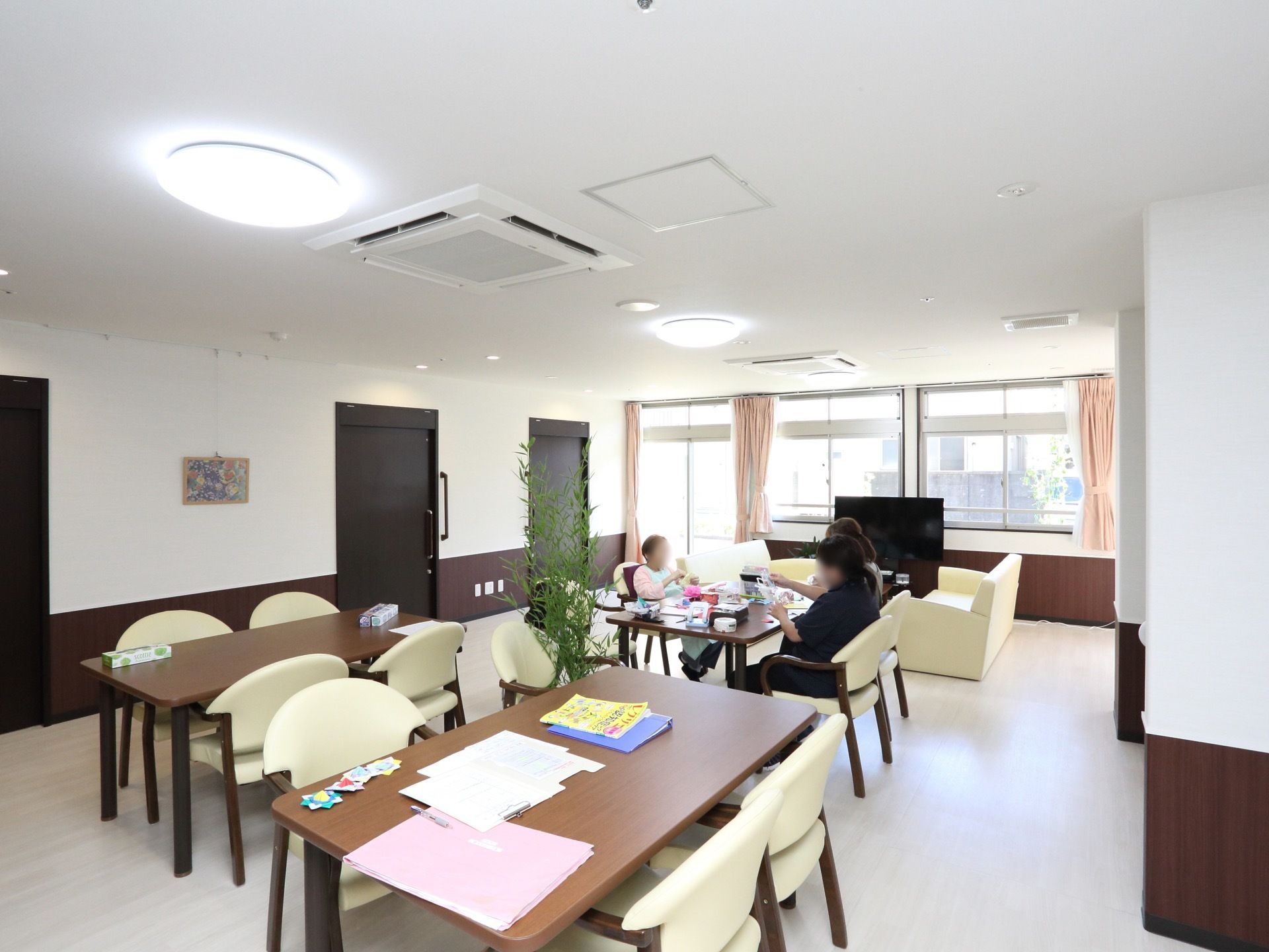 ダークブラウンとホワイトでまとめられた内装が、落ち着いた雰囲気のフロアである。入居者様とスタッフが一緒にイベントの準備をしている。