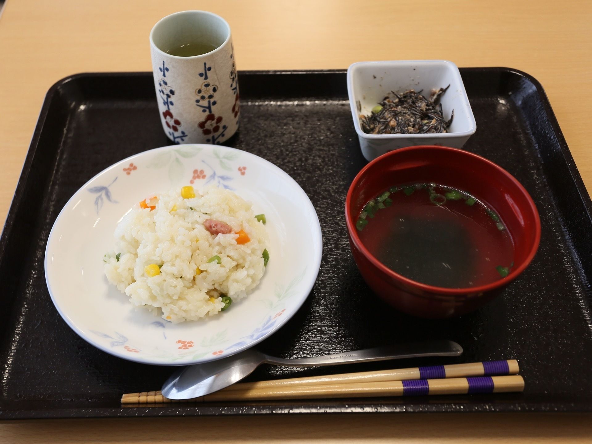 黒いお盆に、食器や箸、スプーン、湯飲みが並べられている。主食は手作りのピラフである。小鉢には、ひじきのサラダが入っている。