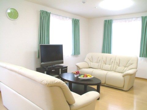 明るい茶色のフローリングの通路の両側に、居室のドアが並んでいる。壁には手すりが備わっている。暖房器具が置かれている。