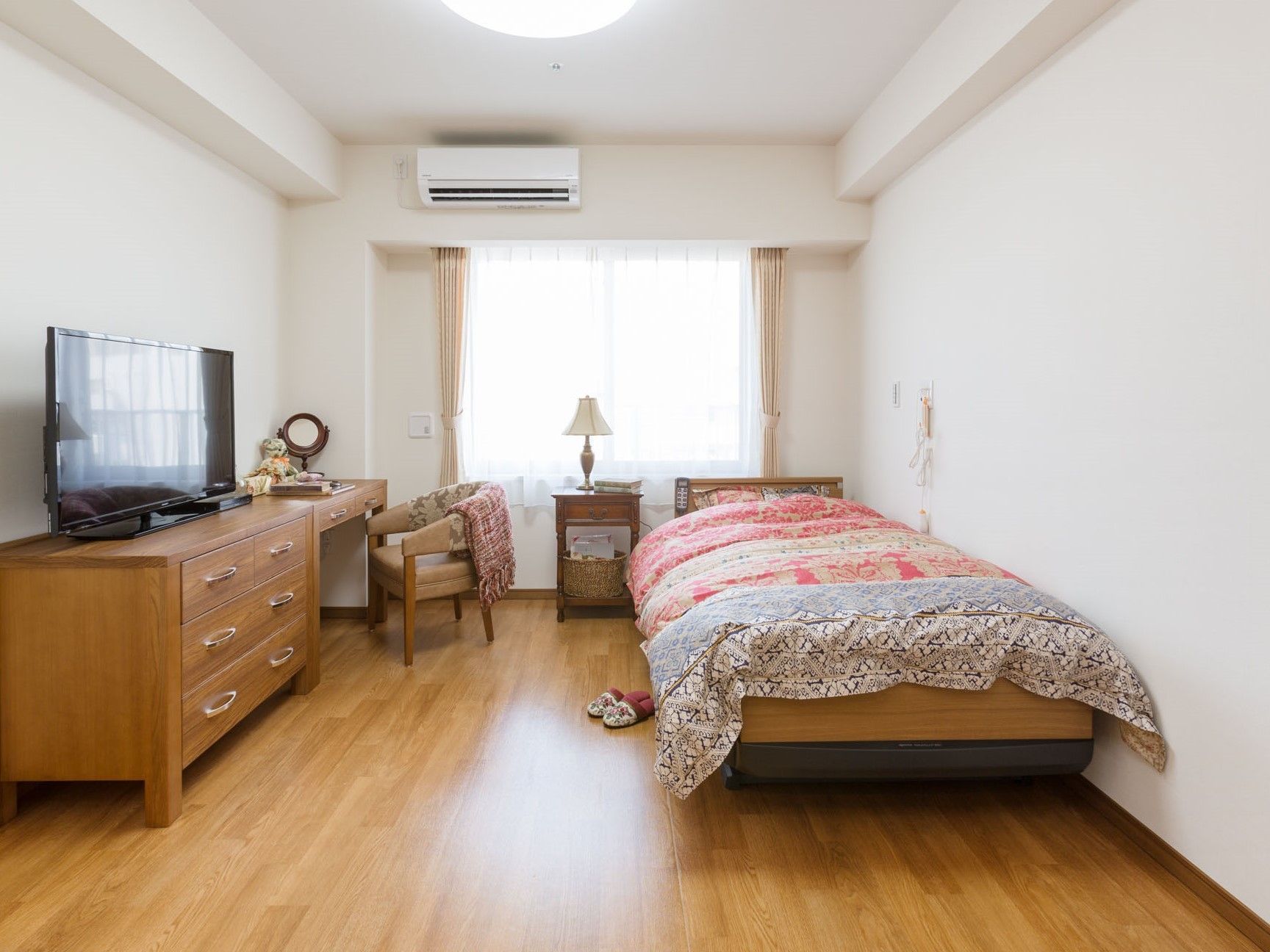 花柄の寝具とスリッパが置かれた、華やかな印象のある居室