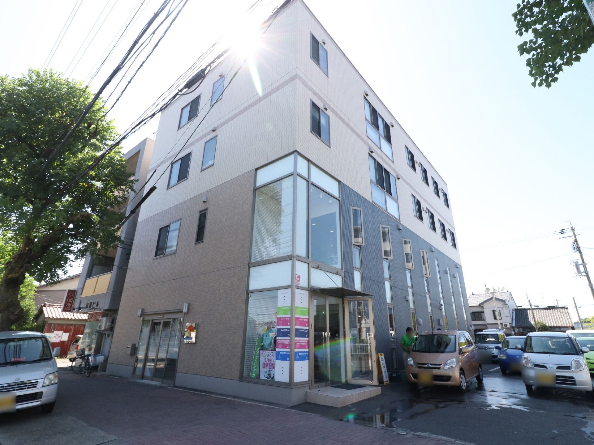 手前角が2階までガラス張りになっている、1、2階がブラウン、3、4階がベージュに切り替えられたビル