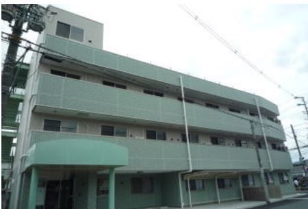 左下に薄い緑のひさしのかかった玄関のある3階建ての建物