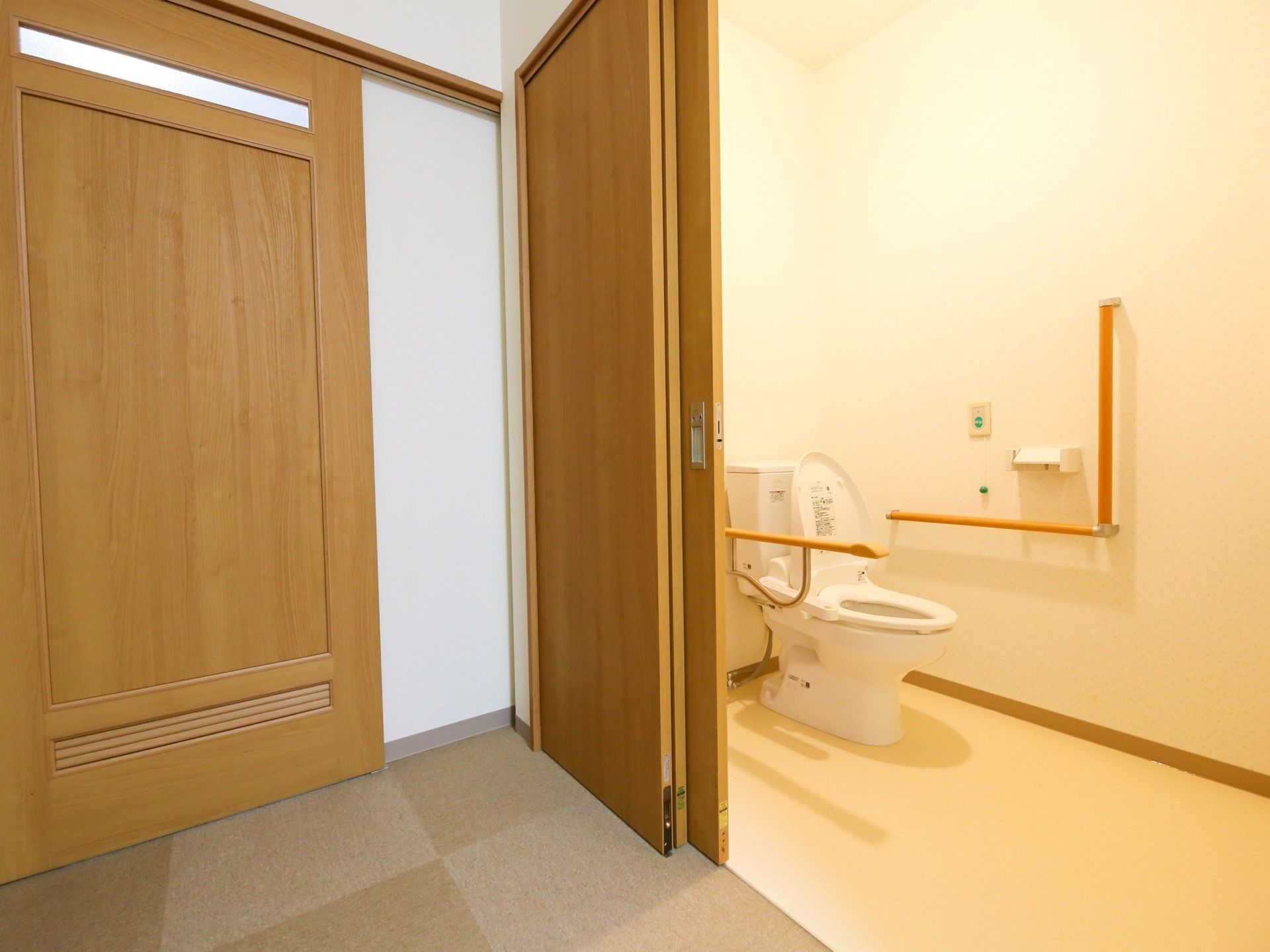 木目調の3枚スライド式扉が設置された居室内のトイレは、開放口が広くゆとりあるスペースを確保している。