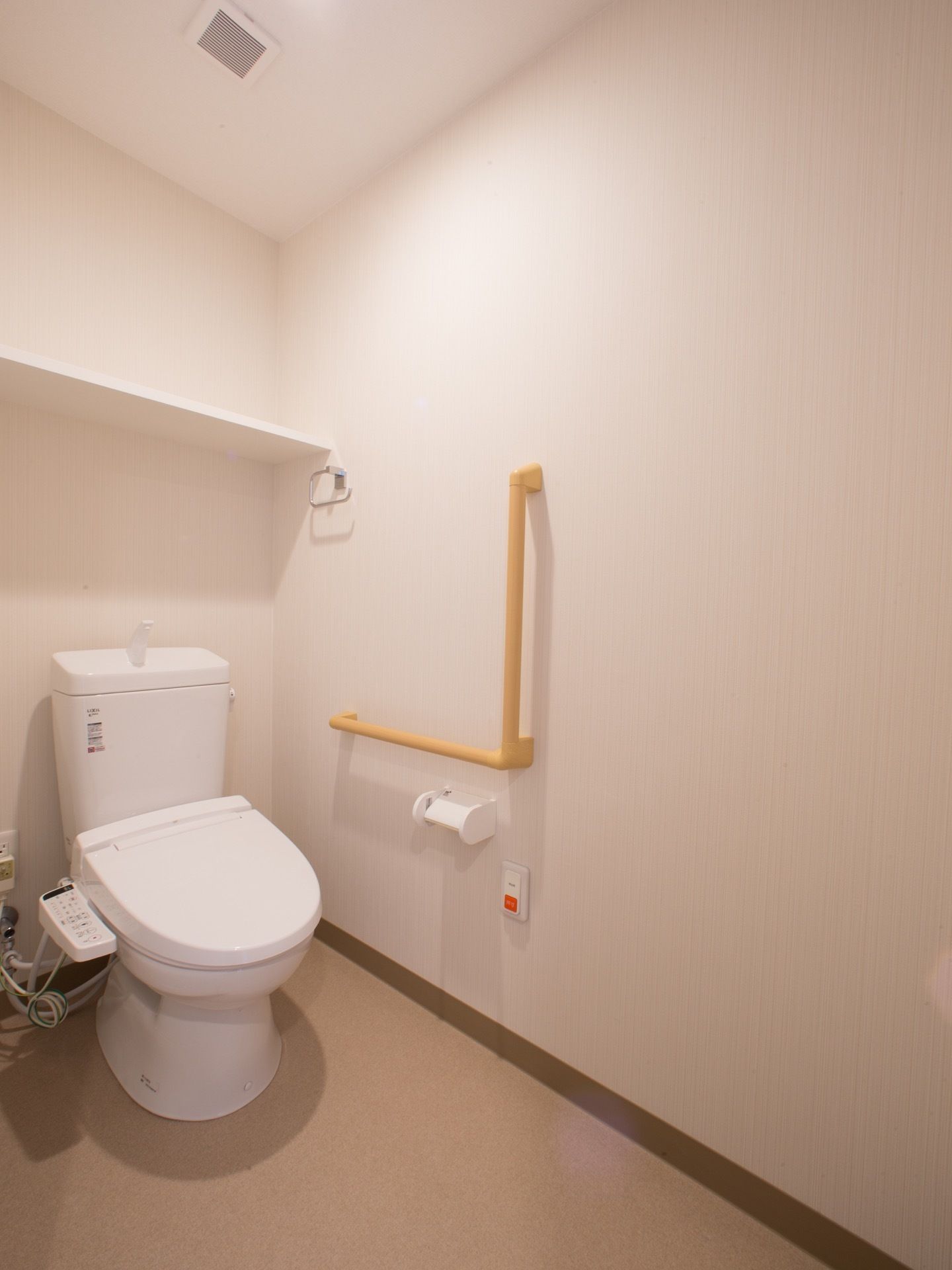 白を基調としており、清潔感のあるトイレにはオレンジ色の呼び出しベルがある。便座の左手の壁には、直角に曲がった手すりも設置している。