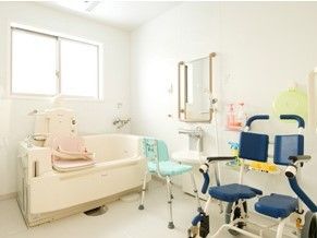 左上に窓があり、白い内装で窓の下に浴槽が置かれた浴室