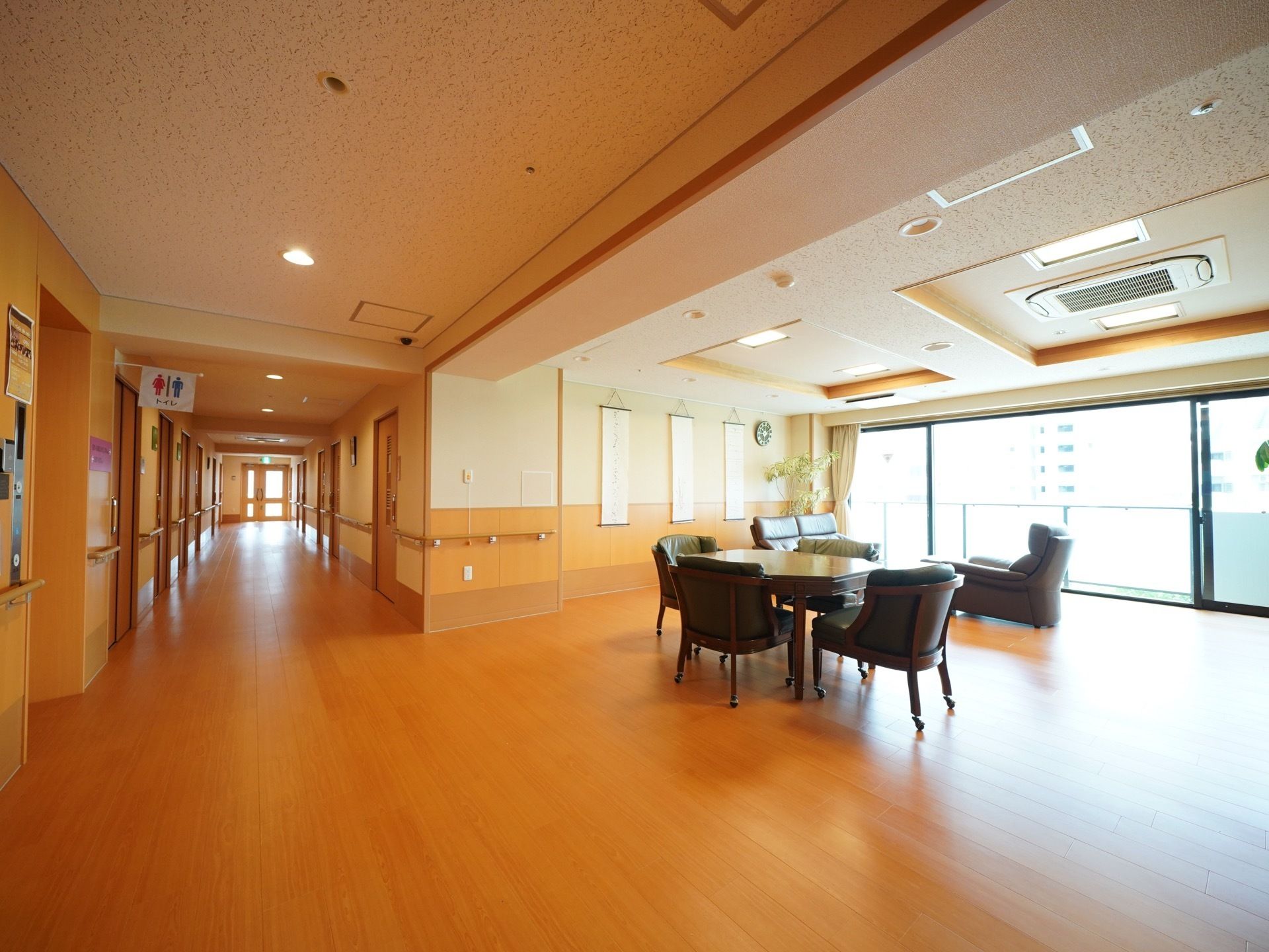 通路に面した広い談話室。大きな窓があるため明るく開放的である。ソファとクッション付きの椅子が４脚置かれたテーブルセットが設置されている。