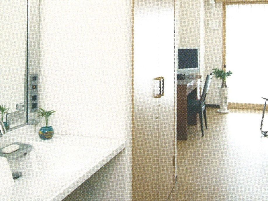 洗面台があり、その上には石鹸や小さな植物などが置かれている。開き戸の収納スペースが洗面台の右隣にある。