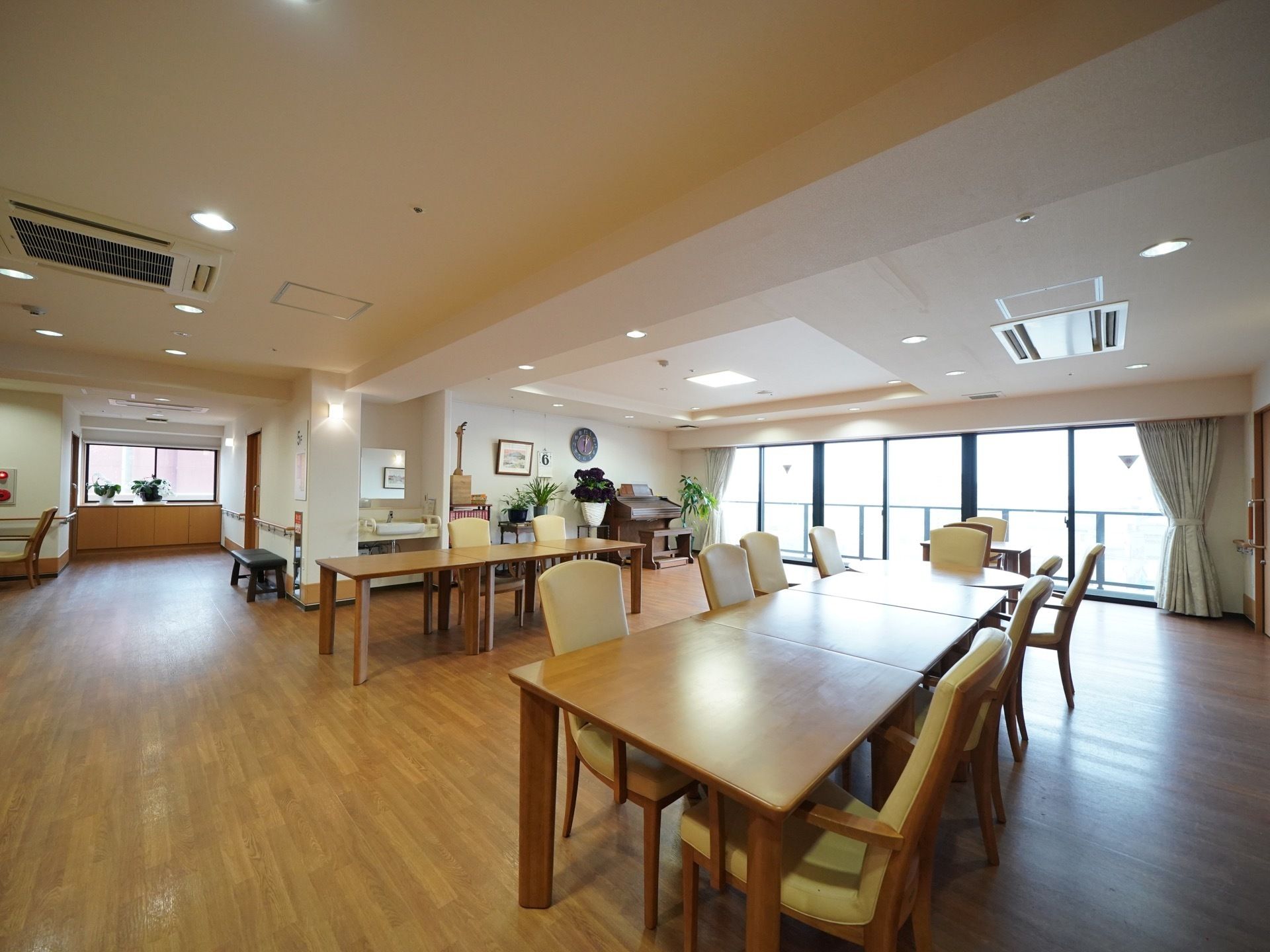窓から十分な光が差し込む明るい部屋である。木目のテーブルと椅子を配置し、その周囲には広々とした空間を設けている。