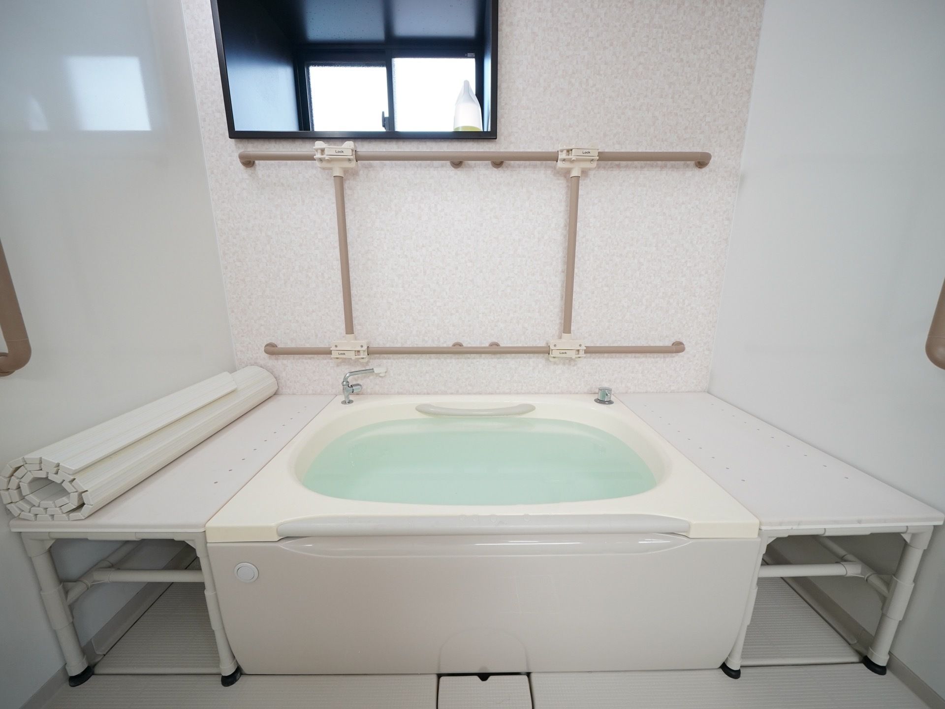 内装色が白基調で清潔感のある浴室である。浴槽上部とその周囲が完全フラットであり、介護仕様の作りとなっている。