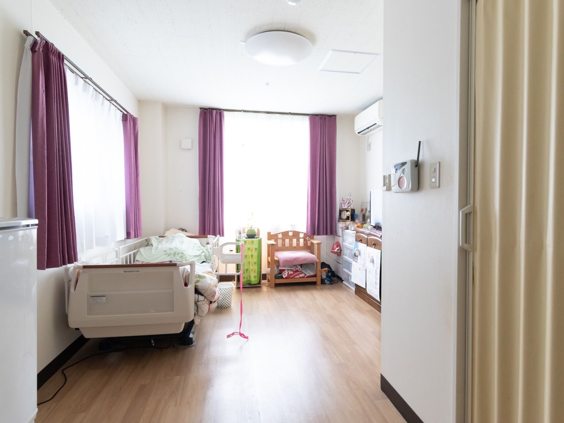 白を基調とした明るい居室となっており、窓には紫色のカーテンがかけられている。家具も白で統一されている。