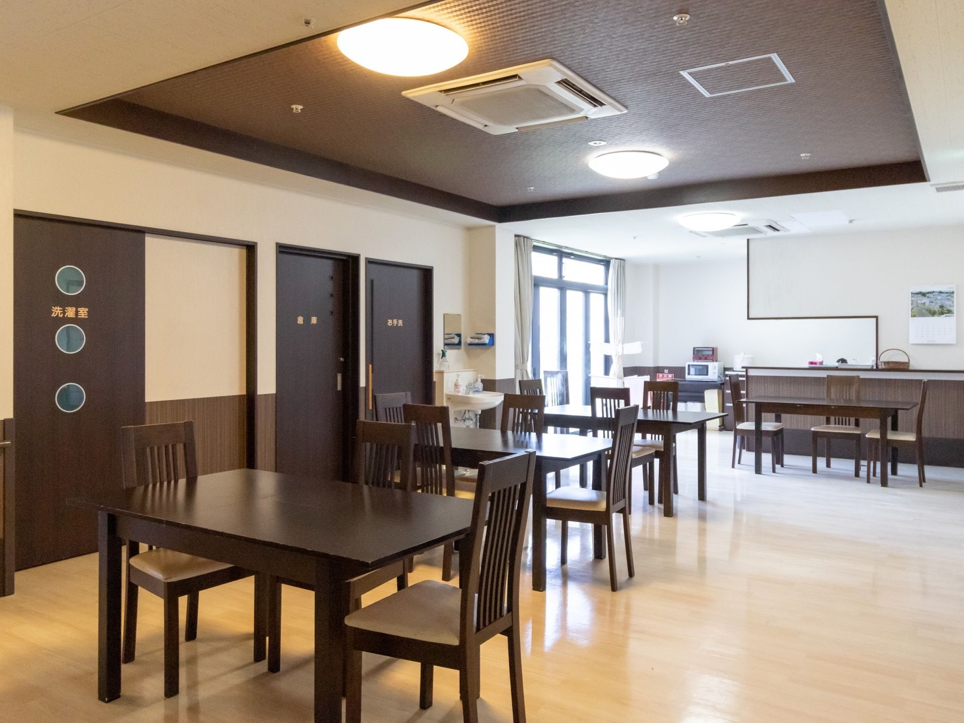 茶系の家具でまとめられた落ち着いた雰囲気のダイニングである。天井には埋め込み式のエアコンが設置されている。