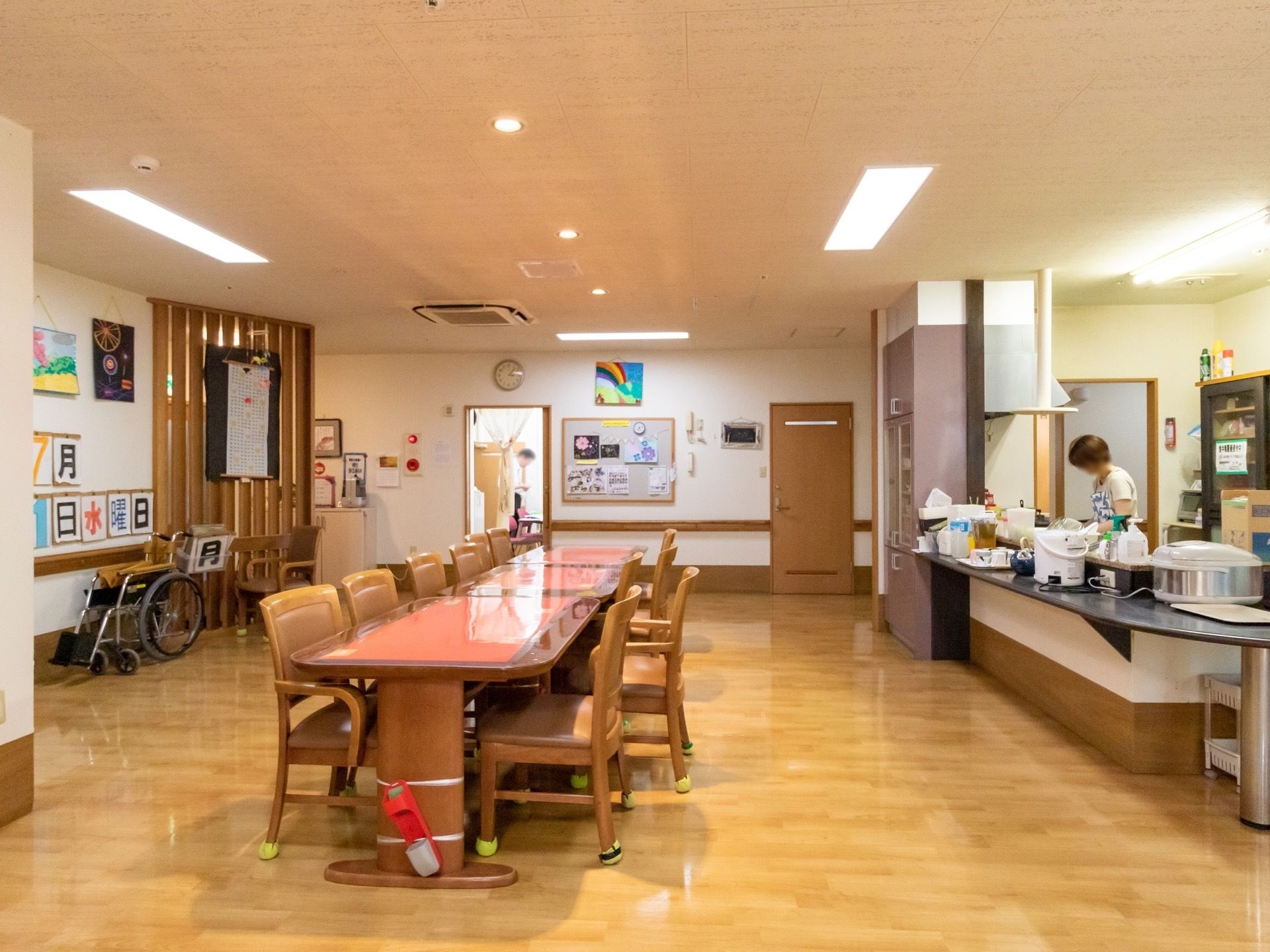 キッチンが併設されていて、複数のテーブルと椅子が並べられている共有スペース。各家具はゆったりとした間隔をもって設置されている。