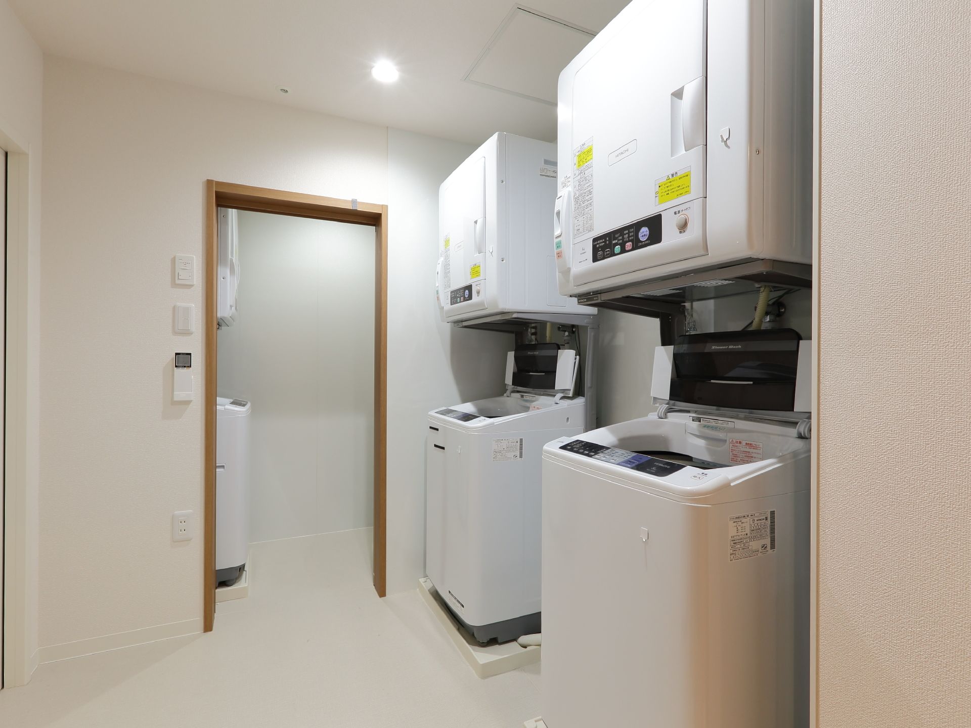 白が基調のランドリールームには、全自動の洗濯機と大型乾燥機が2台ずつセットで置いてある。照明などのスイッチパネルは大きくてわかりやすい。