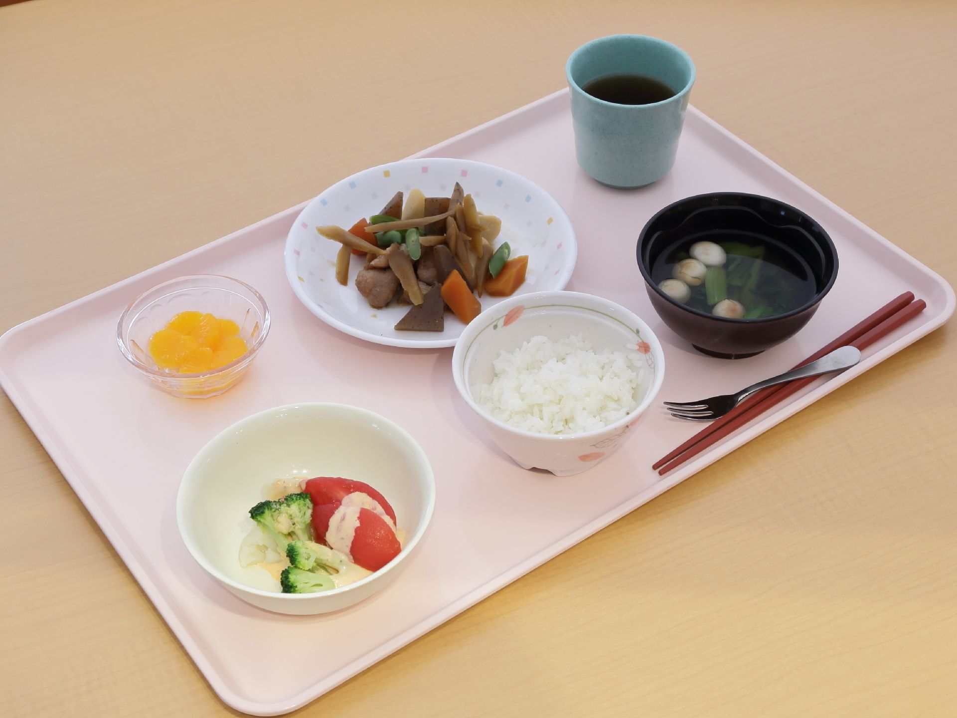 白いご飯、お吸い物、根菜の煮物、野菜サラダ、果物のデザート、お茶がある。野菜を中心とした、身体に優しく栄養バランスのとれた食事になっている。