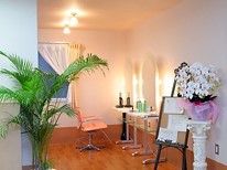 入り口には観葉植物や立て看板などが置かれており、お店のような雰囲気になっている。奥にある椅子の手前には化粧台が置かれている。