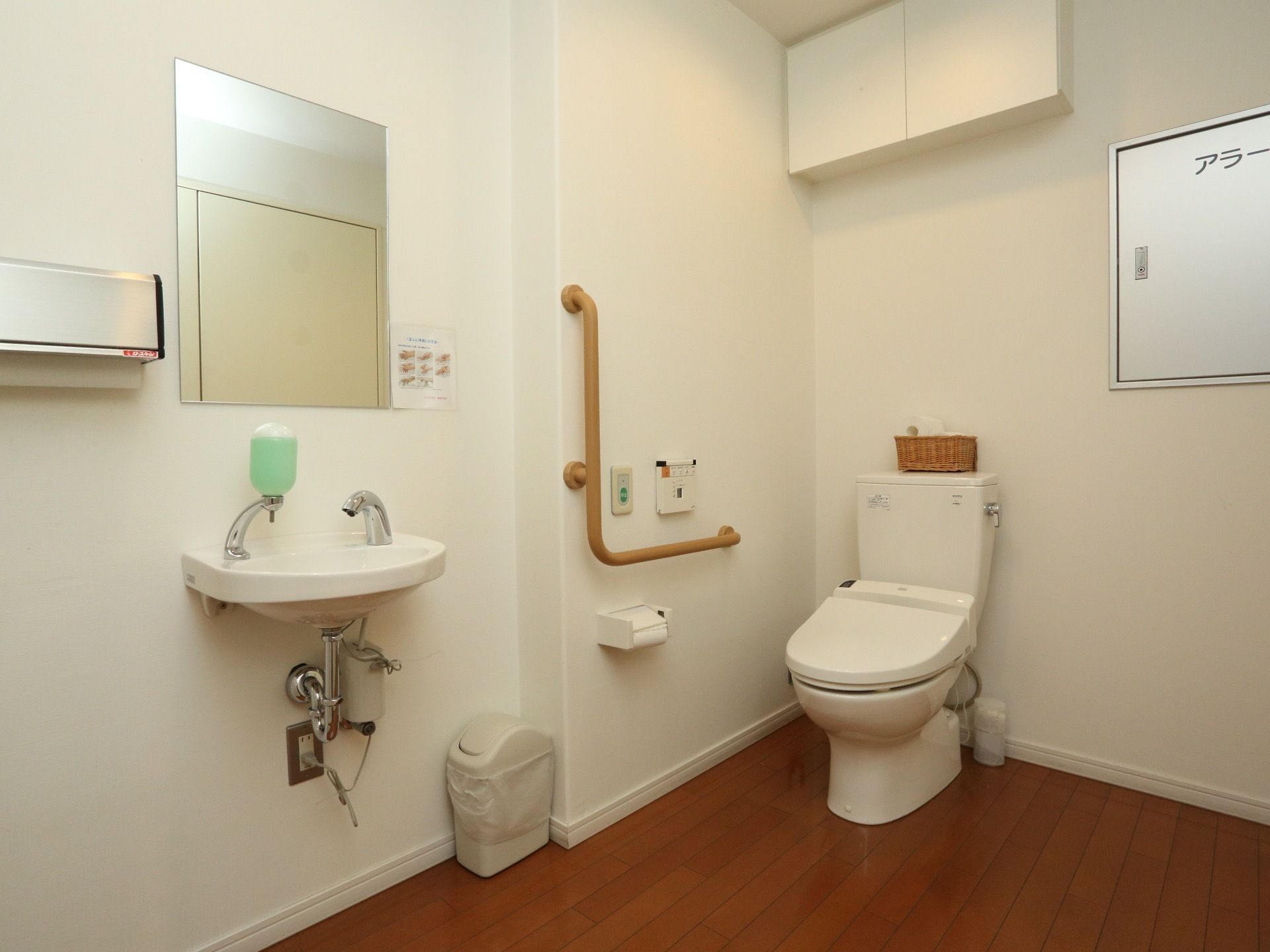 清潔感のあるトイレになっている。便座の隣には手すりが取りつけられており、手洗い場や鏡も設けられている。