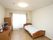 居室は白い壁紙とナチュラルカラーのフローリングで、シンプルな部屋である。壁側にはチェストが置かれ、その上にテレビや置物がある。
