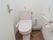 トイレには洋式便器便器が設置されている。壁側にはL字型の手すりとトイレットペーパーがある。手すりの上側には呼び出しボタンがある。