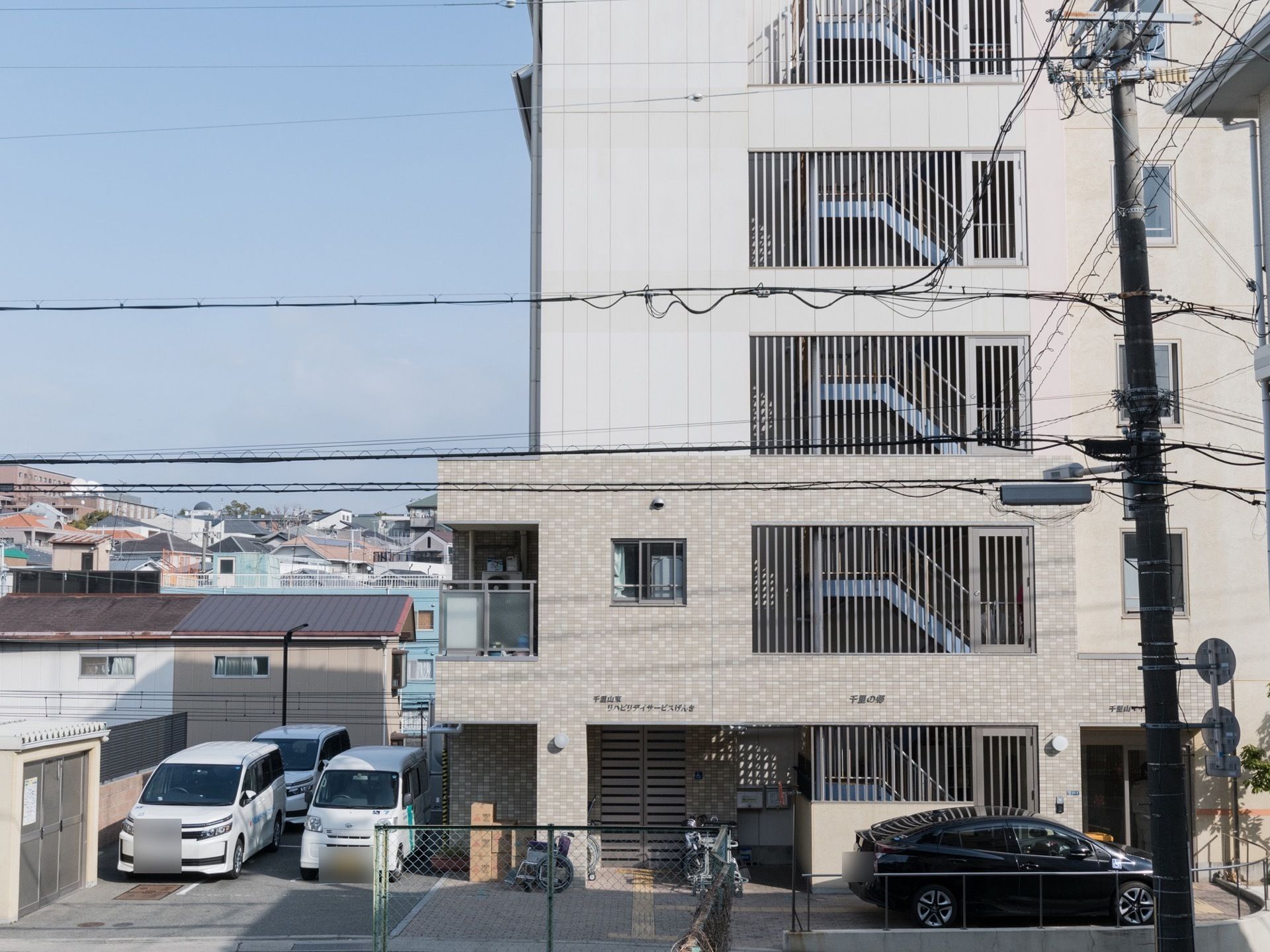 フェンスに囲われた外階段がある1、2階と3階以上で外壁の色が切り替えられた建物
