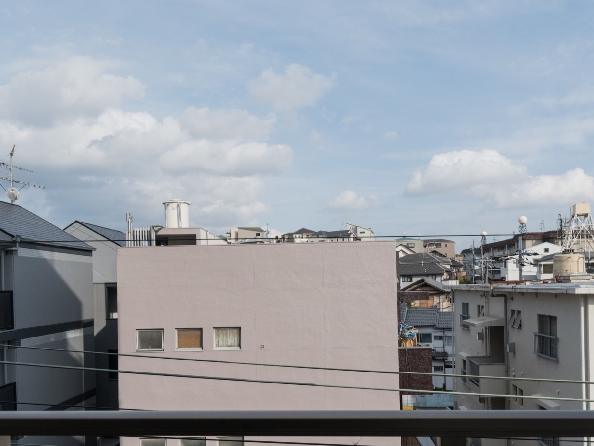 手前に横に伸びる手すりがあり、上半分が空、その下に建物が並んでいる景観