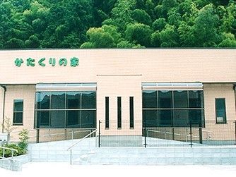 玄関には、段数の少ない階段や緩やかなスロープ通じてアプローチすることができる。建物正面の壁には施設の名称が鮮やかな緑色で表示されている。