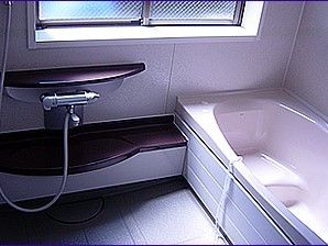 壁や床面がグレーの配色で統一された、落ち着いた雰囲気の浴室である。壁に備え付けられたシャワー台は、通常より低めの位置に設計されている。