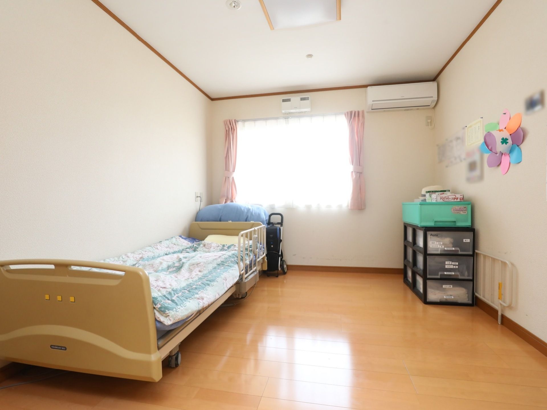 窓から光が差し込む明るい居室である。ベッドが設置されており、転落防止用の柵を取り付けている。エアコンがあり、快適に過ごすことができる。