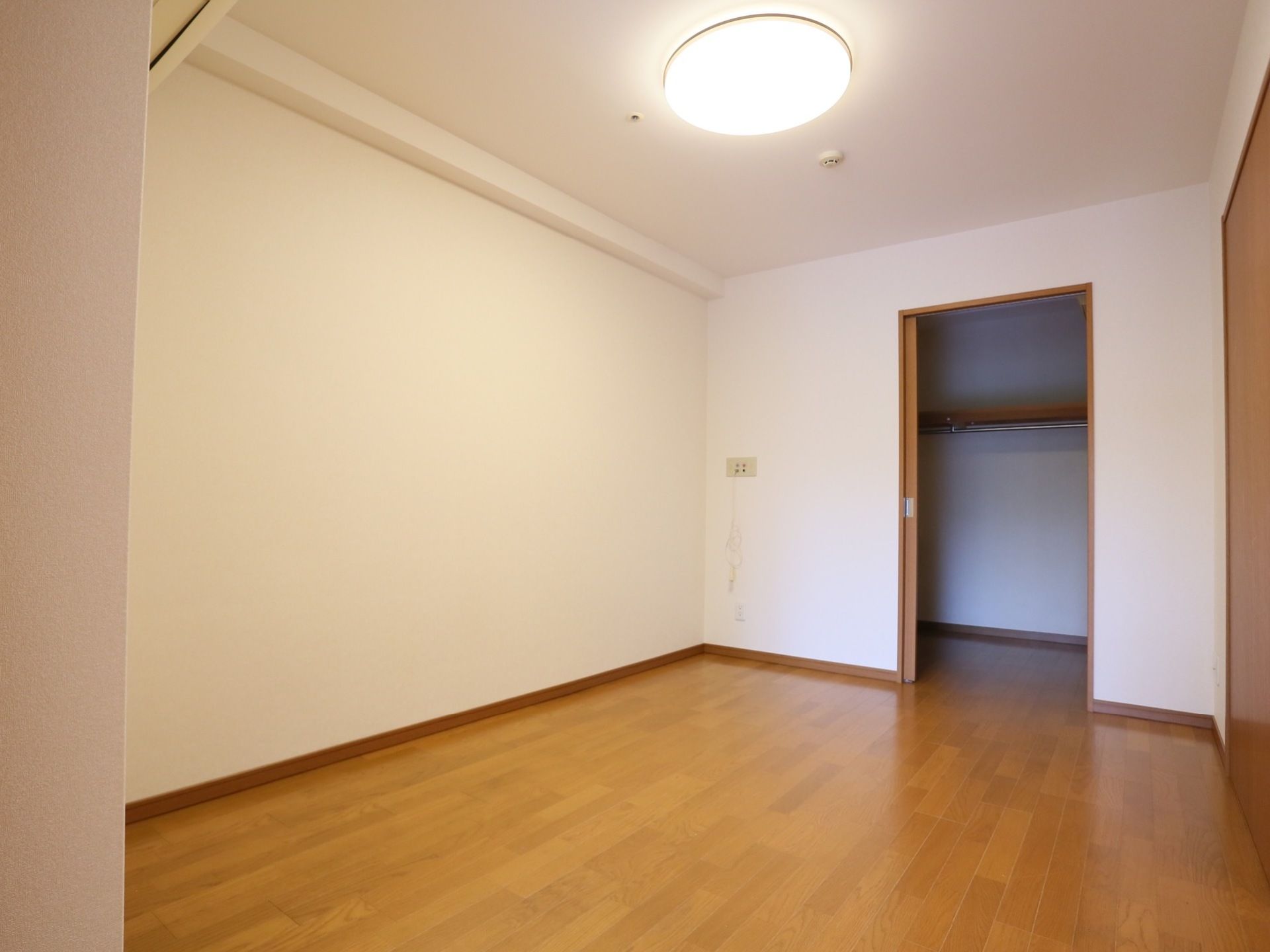 木目調のフローリング部屋である。壁は白くシンプルなデザイン。ウォークインクローゼットも完備されている。