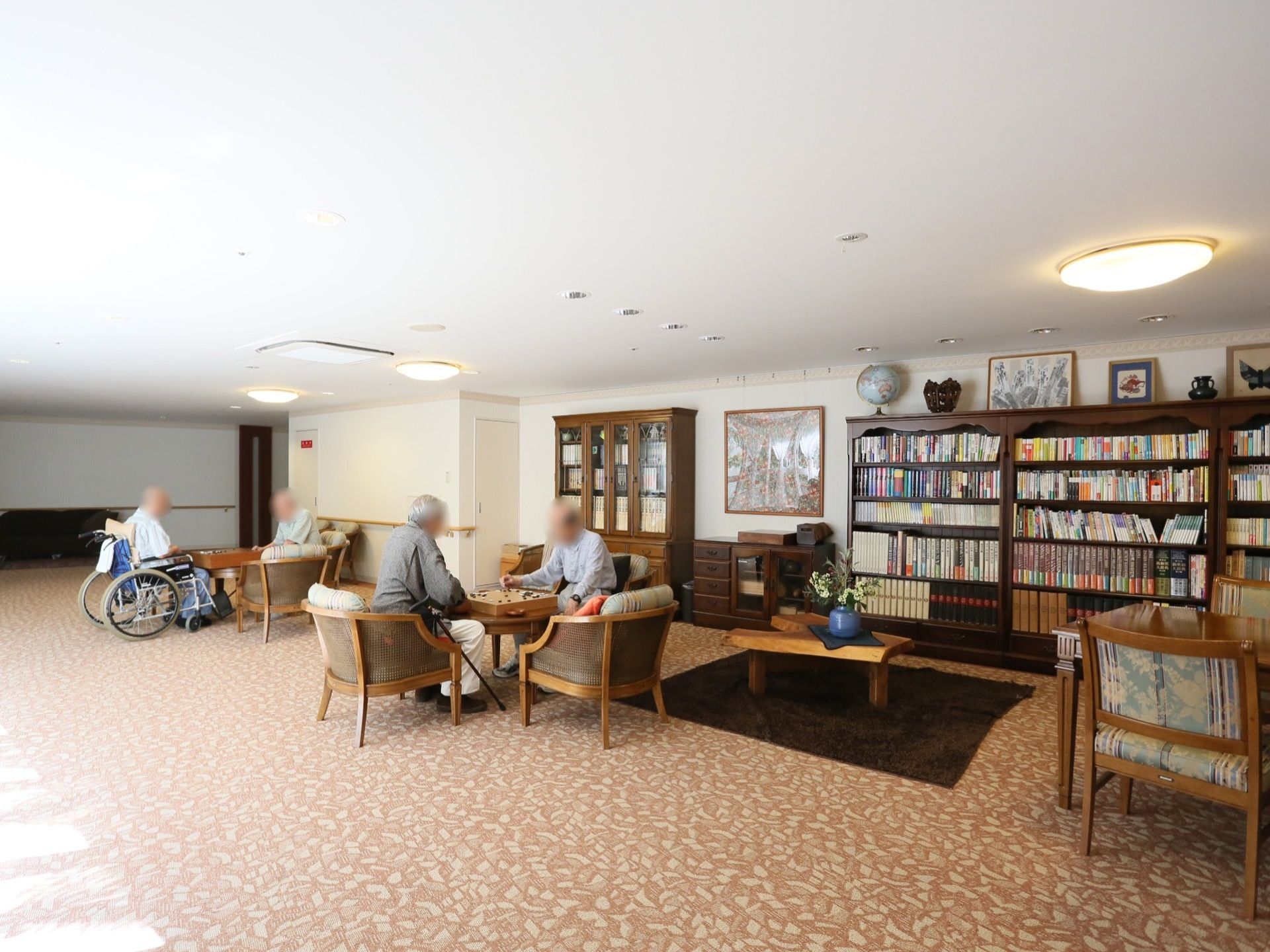 あたたかい色合いのクッションフロアに、白色の壁でコーディネートされた落ち着いた空間である。本棚にたくさんの本が並べられている。