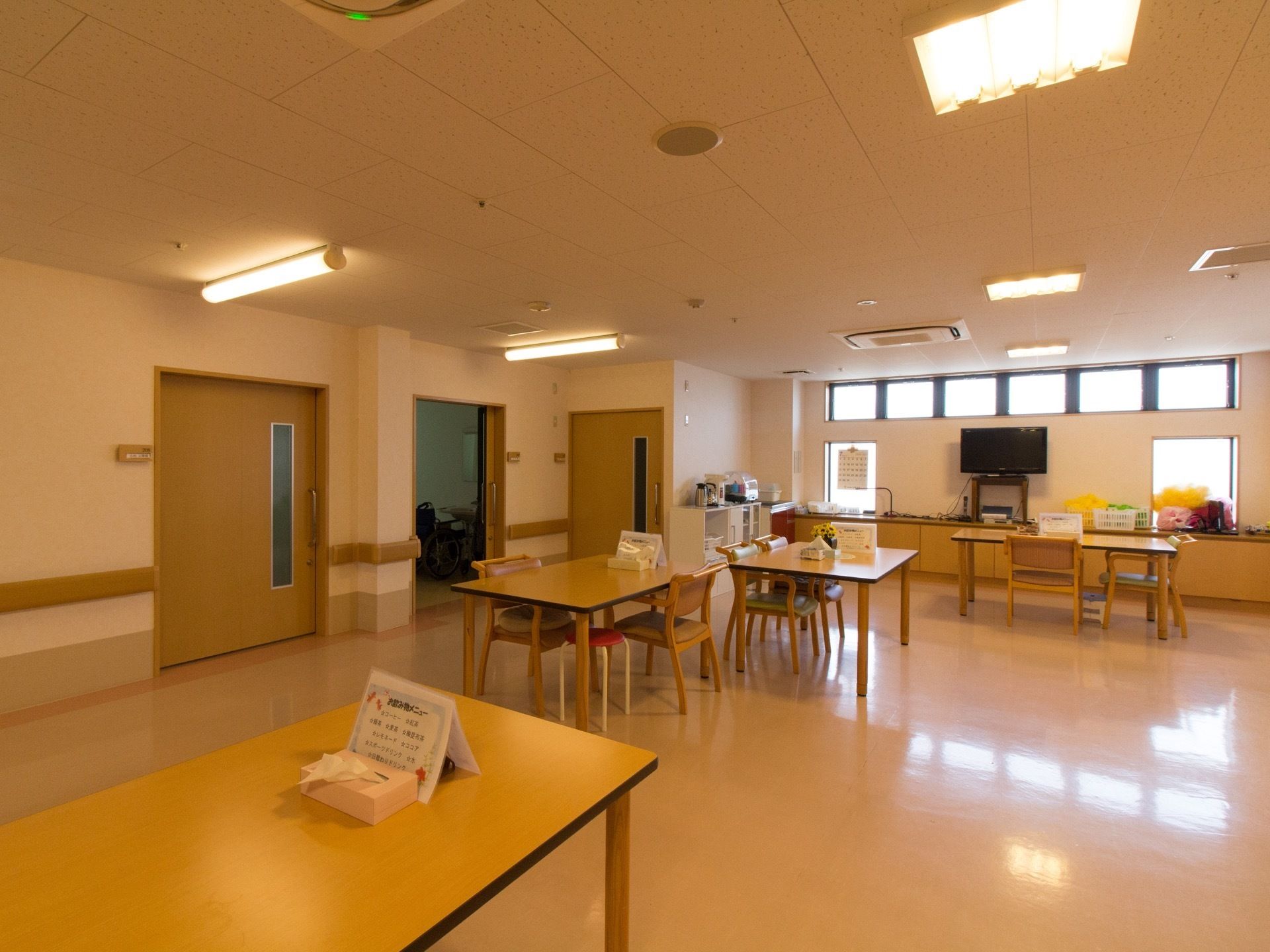 広々とした食堂に、テーブルや椅子が間隔に余裕をもって設置されている。壁際にテレビや炊飯器が置かれている。