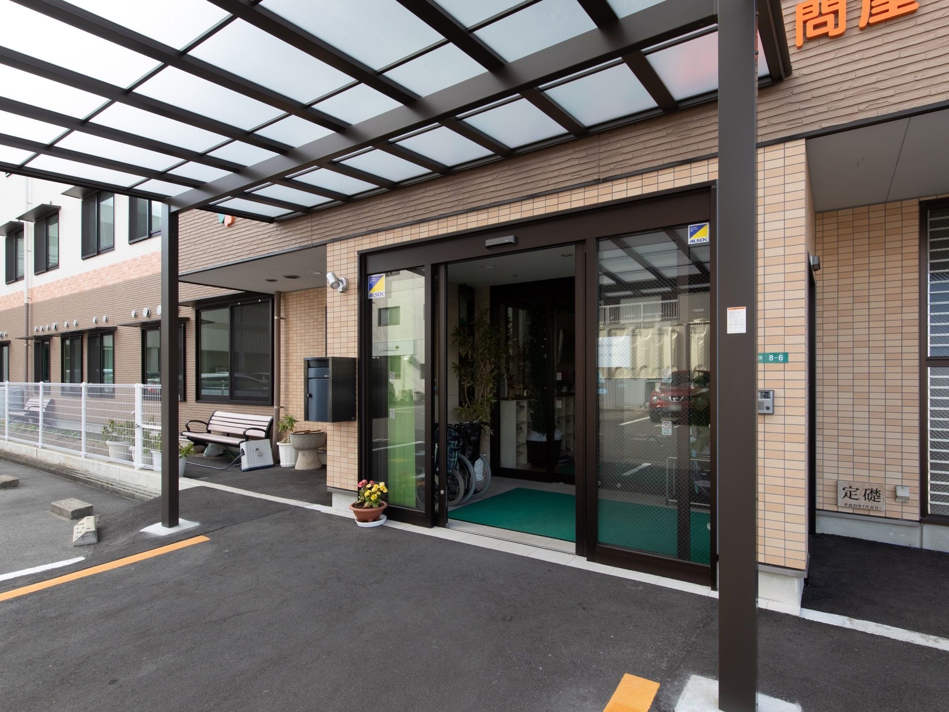 ブラウンが基調の新しい建物である。エントランスの扉は間口の広い自動ドアである。周辺はアスファルトで舗装されている。