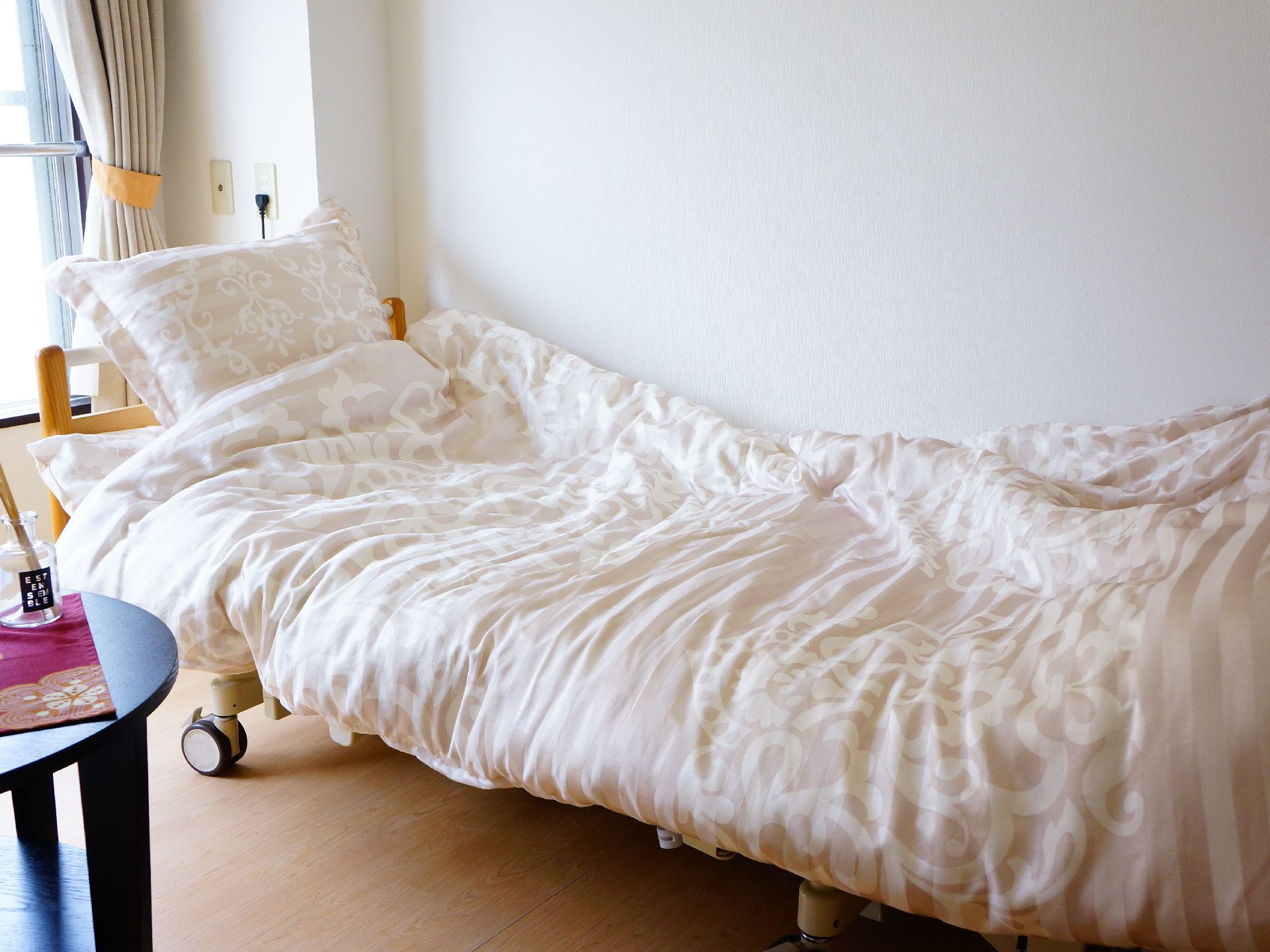 日当たりの良い居室に、ベッドとテーブルが置かれている。ベッドの高さはローテーブルと同じぐらいの高さに設定されている。