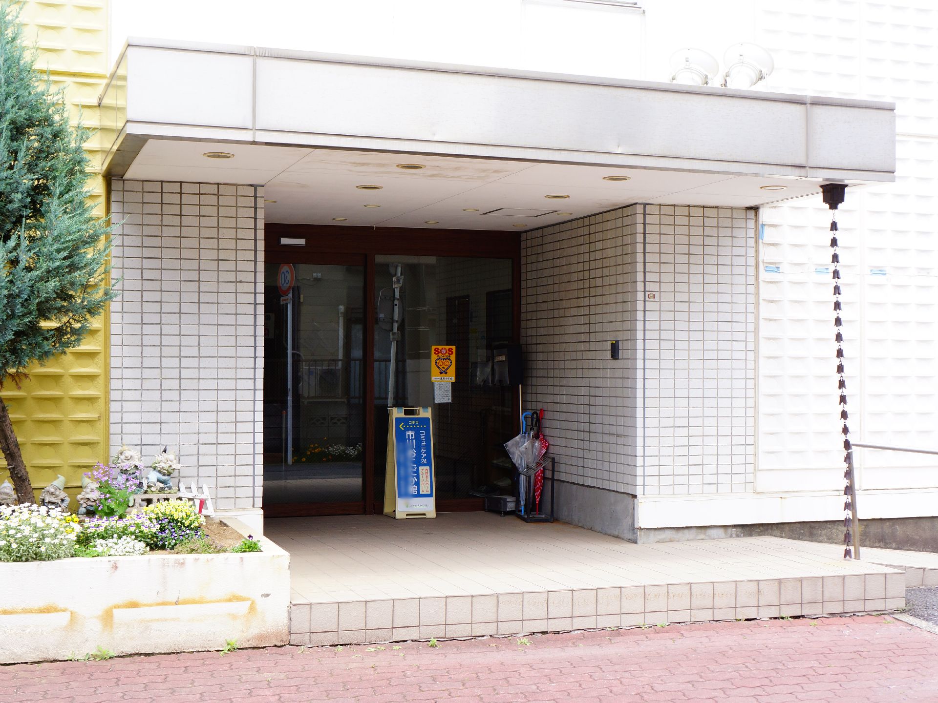 玄関横よりスロープを登り切ると、脇には花壇があり、色とりどりの花が植えられ、小人の置物がおかれている。