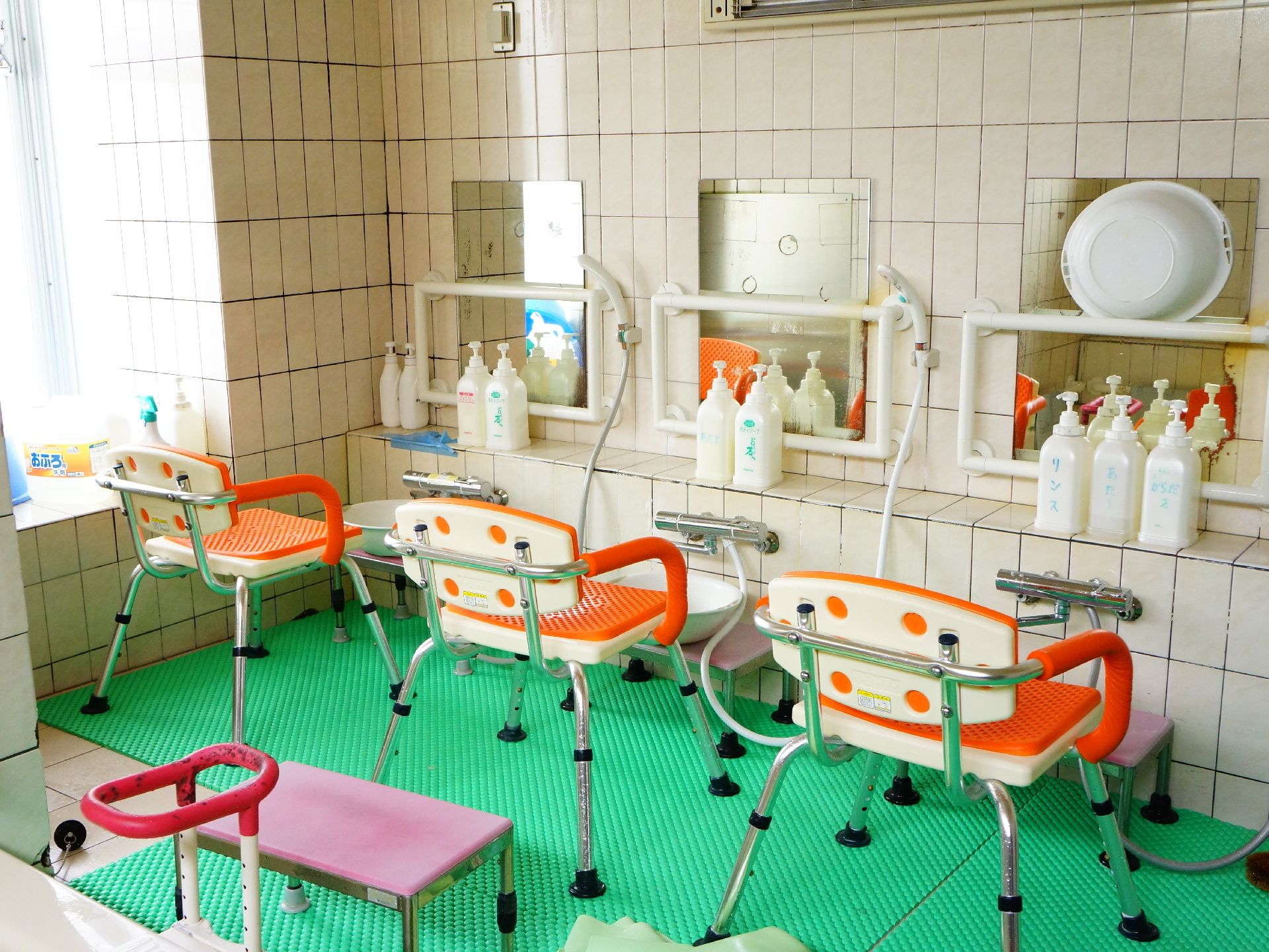 浴室内には洗い場が3つあり、オレンジ色の肘掛つき椅子が3つ、シャワーも3つある。大きな窓があり、日差しを感じながら入浴ができる。