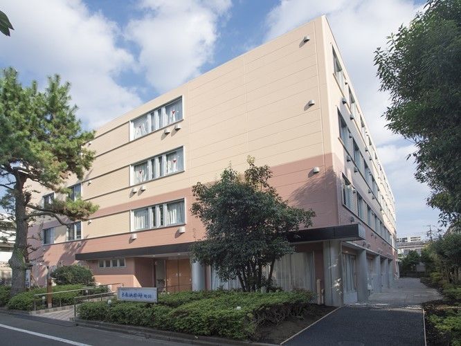 1、2階がライトブラウン、3、4階がベージュに切り替えられた外壁を持つ4階建ての建物