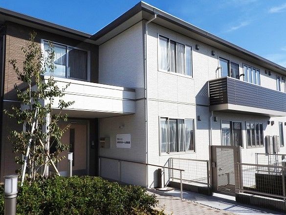 施設の入口に真っ直ぐ通じるアプローチには手すりが備え付けられている。建物の２階部分には一部ベランダが設置されている箇所がある。