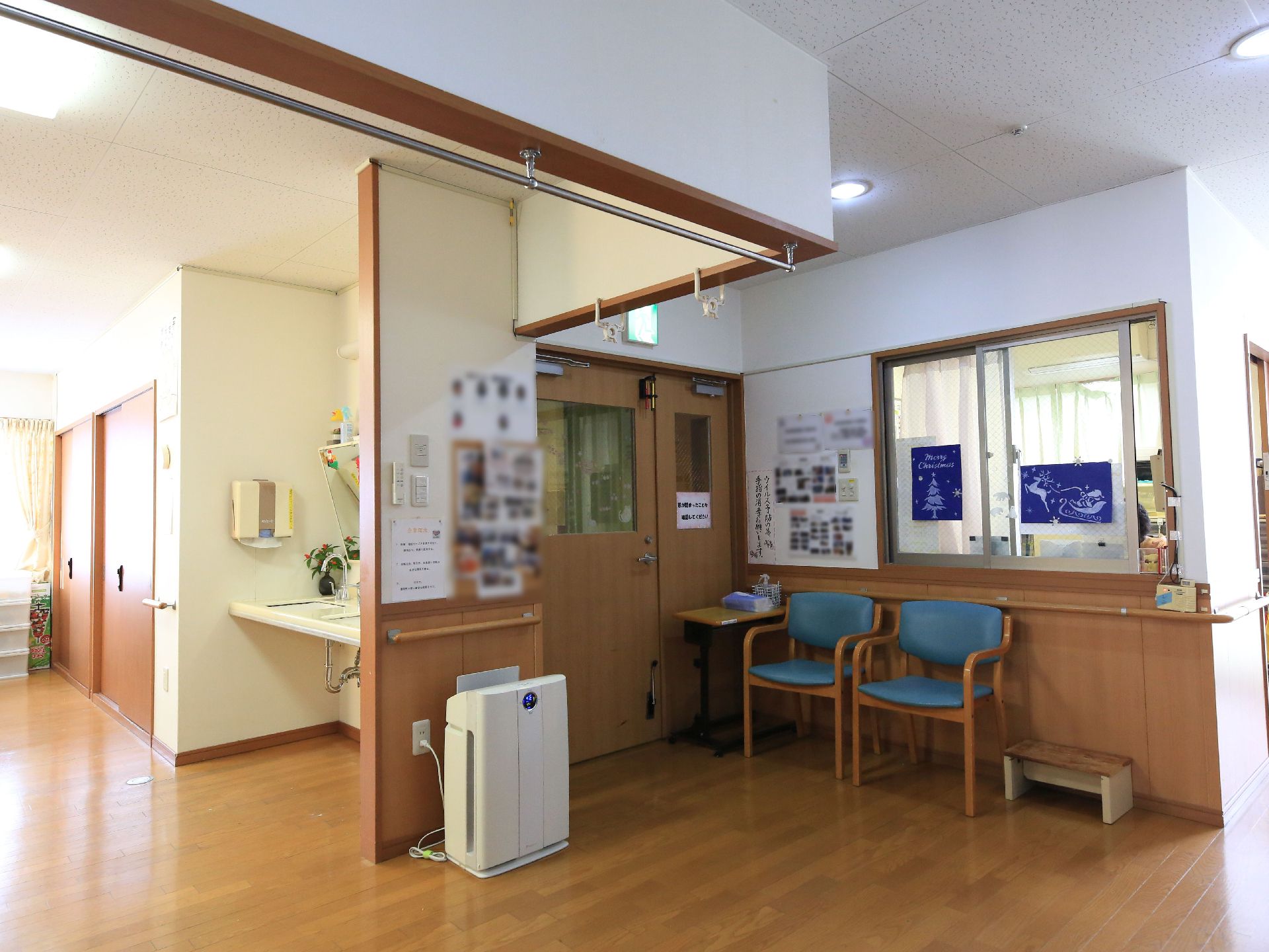 受付は透明なガラス窓になっている。その前には、背もたれとひじ掛けがある椅子が２つ置かれている。空気清浄機がある。