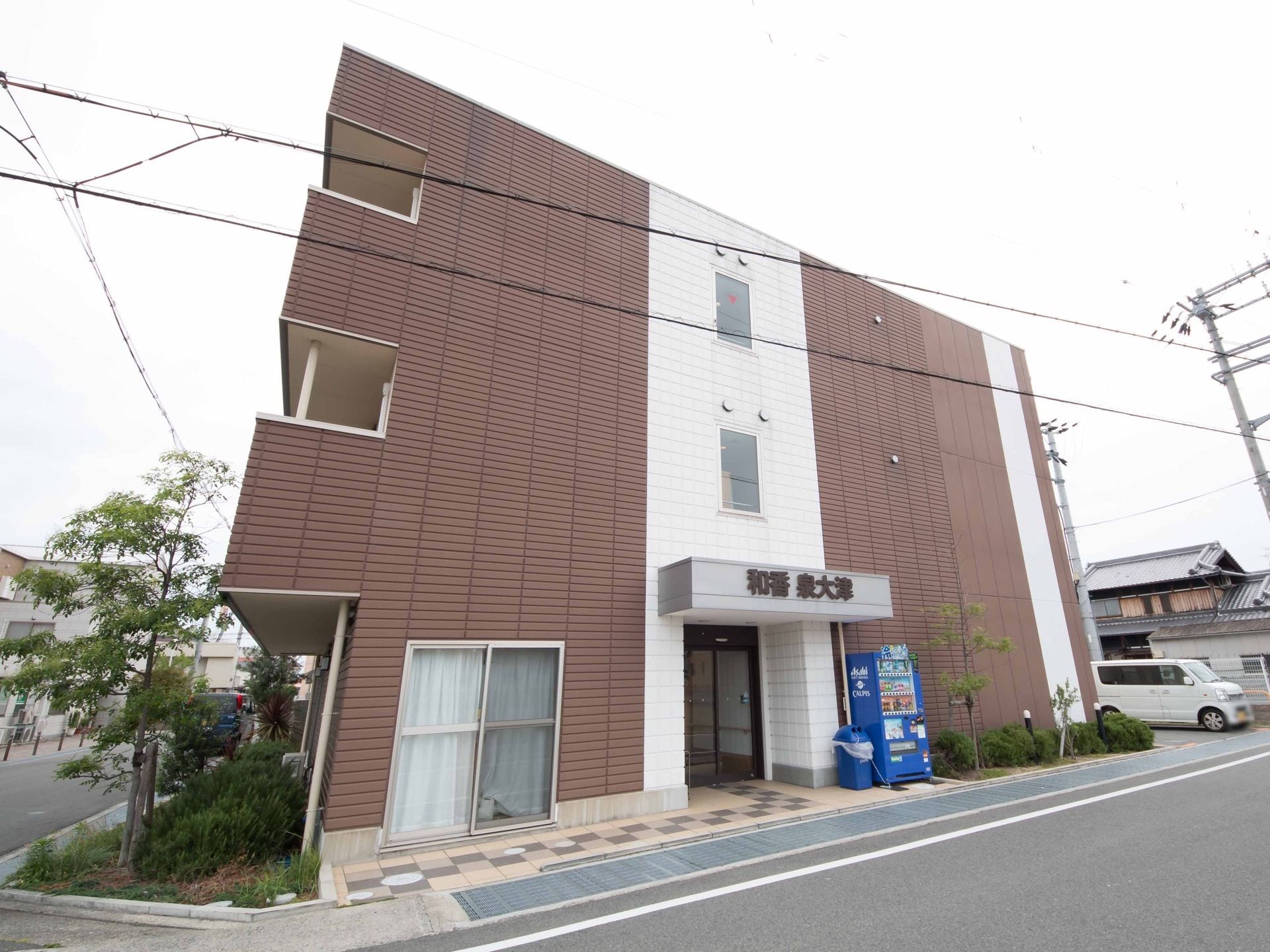 建物の傍に種類の異なる庭木を植え込み、緑豊かな空間を設けている。上階にはベランダを備え、フェンスを設置している。