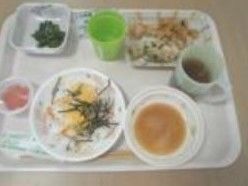 トレーの上には豊富な品数の食事が並べられている。コップは持ち手が付いたプラスチック製で、入居者様が使用しやすいよう工夫されている。