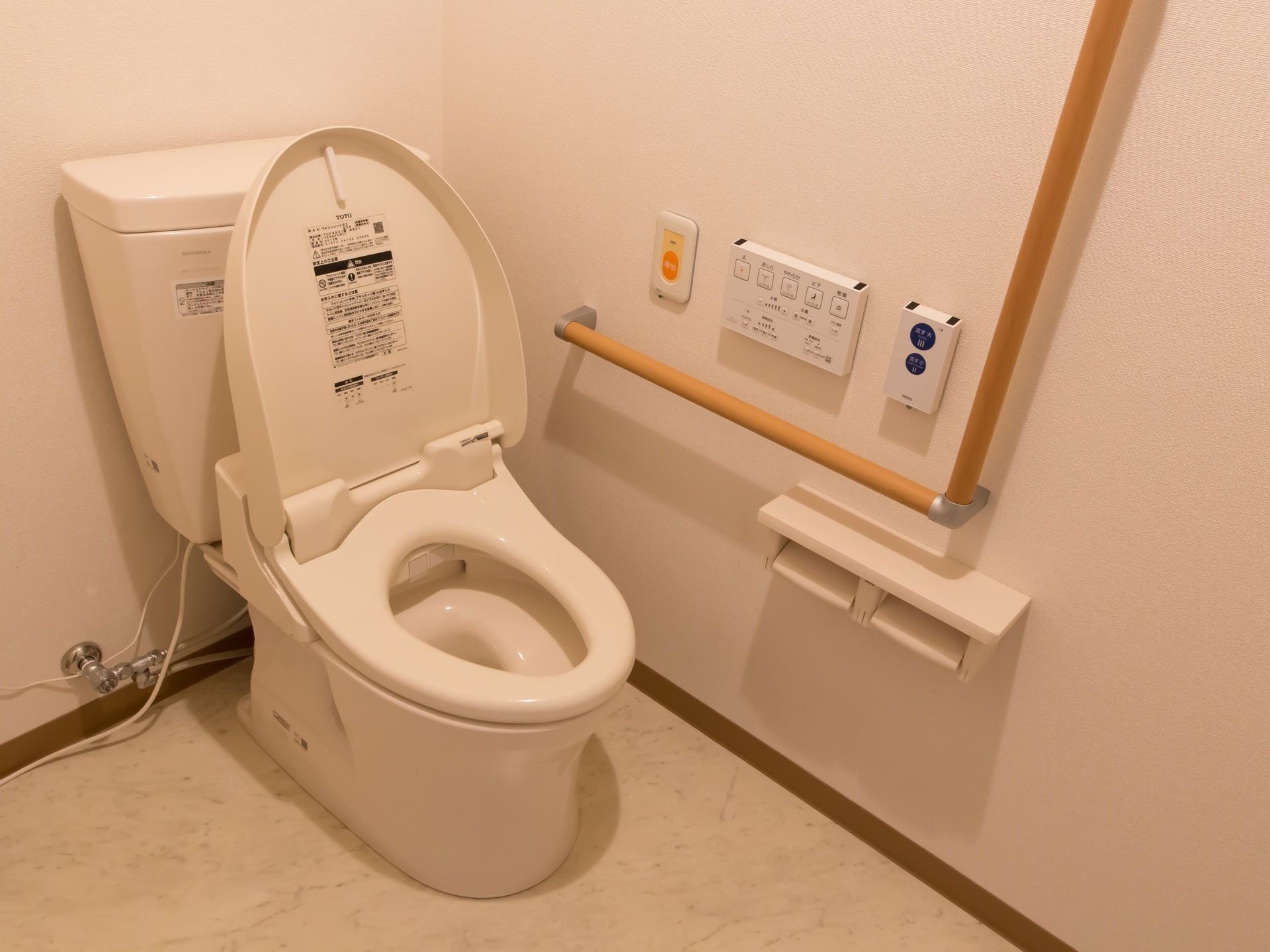 トイレには、温水洗浄便座器が完備されている。壁には、安全にご利用いただけるようＬ字型手すりや緊急ブザーが設置されている。