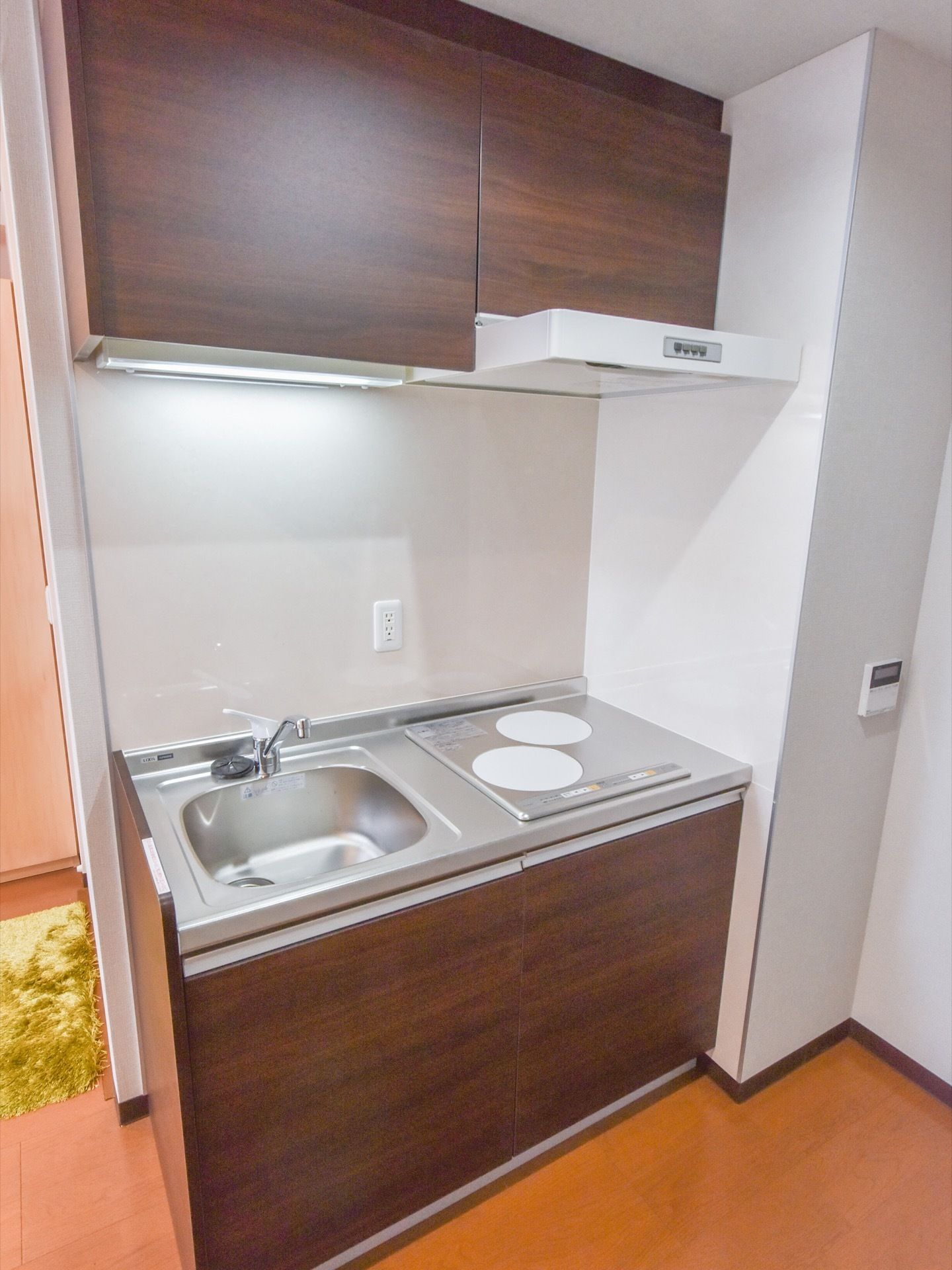 居室には、木目を基調としたキッチンが設置されている。IHコンロを採用しており、換気扇や流し、収納もしっかり設置されている。