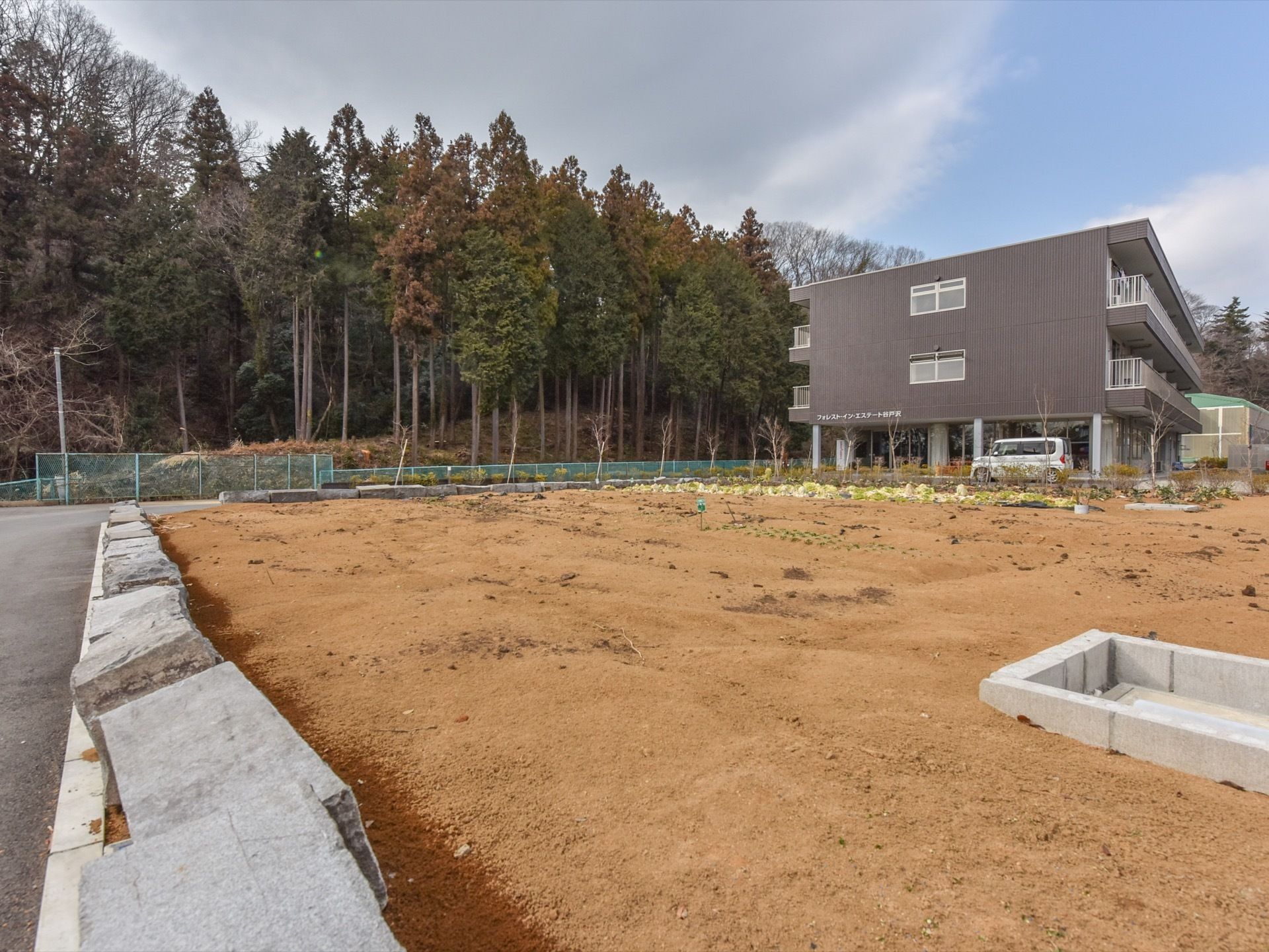 施設の外観からは、濃いブラウンの壁が特徴的な、おしゃれで落ち着いた雰囲気を感じられる。施設の敷地内に、広い畑も備わっている。