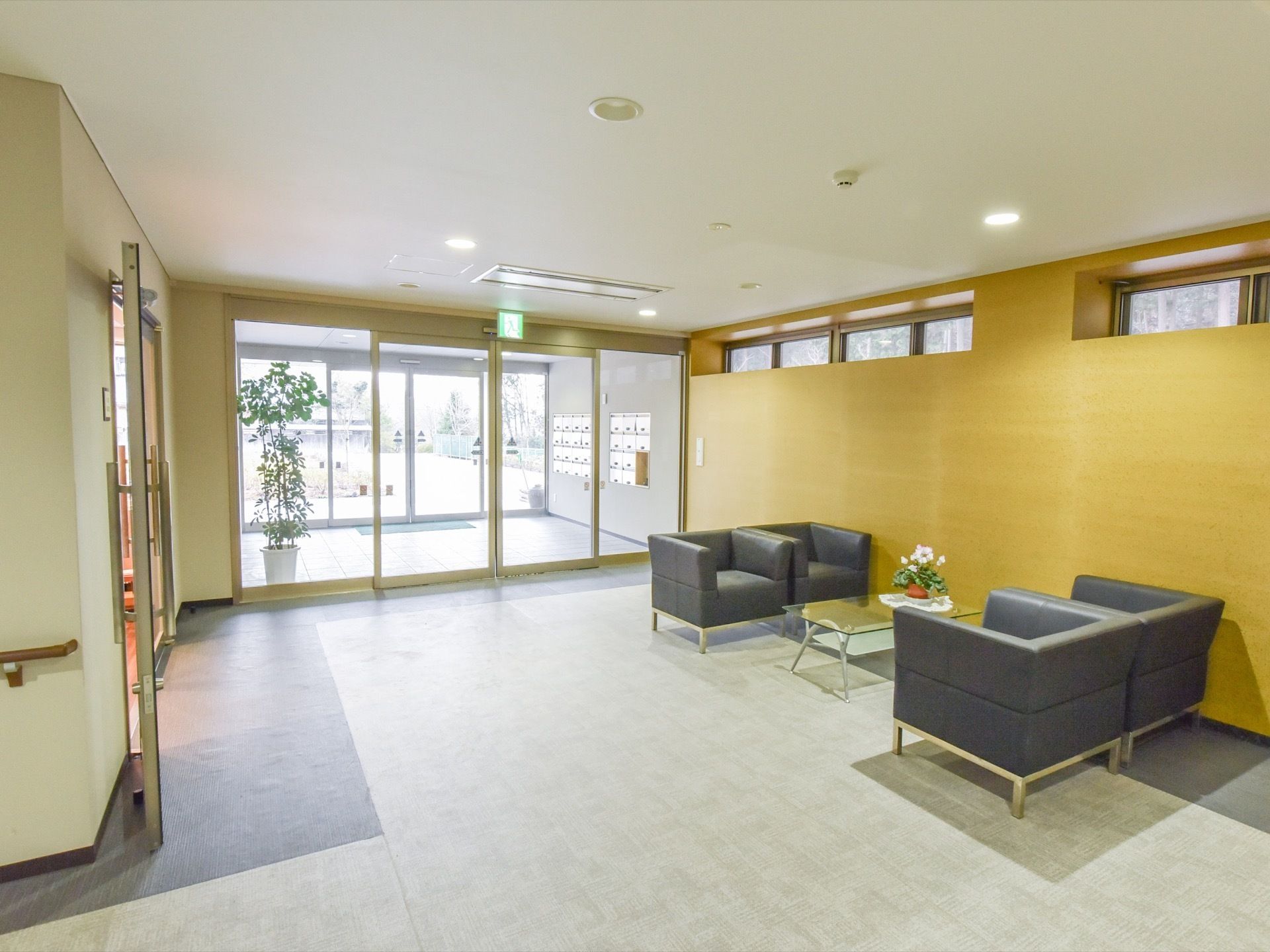 風除室には、各部屋の郵便受けがある。施設の中に入ると広い空間があり、テーブルとソファが設置されている。