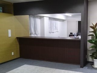 グレーの床、黄土色の壁が左にあり、向こう側が見える黒っぽいカウンターで仕切られたスペース
