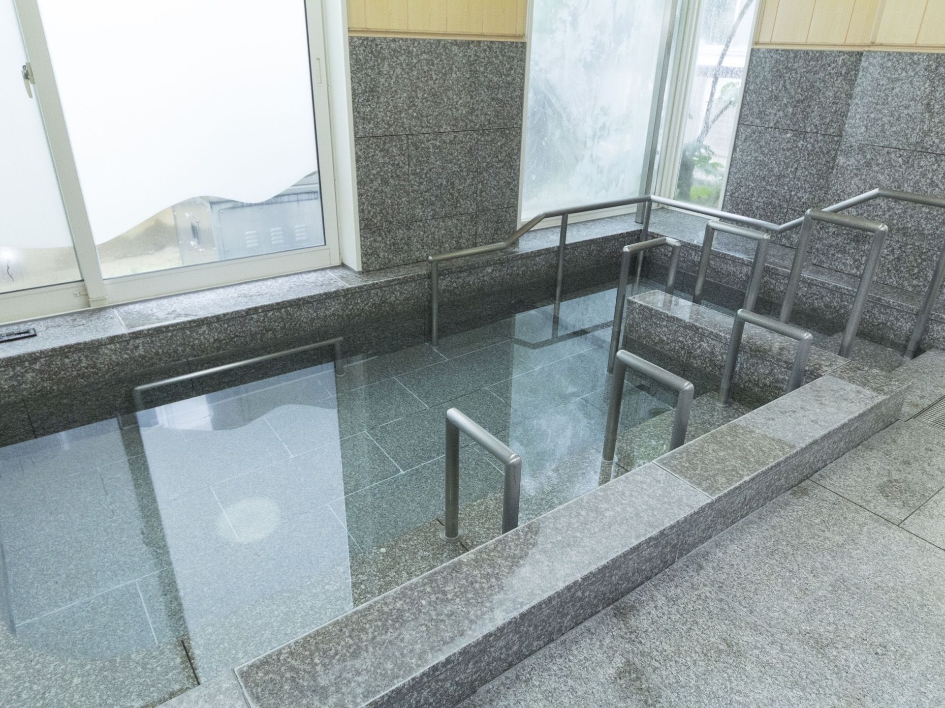 大きな窓に面した浴槽は広くゆったりとしている。安全に浴槽への出入りができるように手すりが数か所に設置されている。